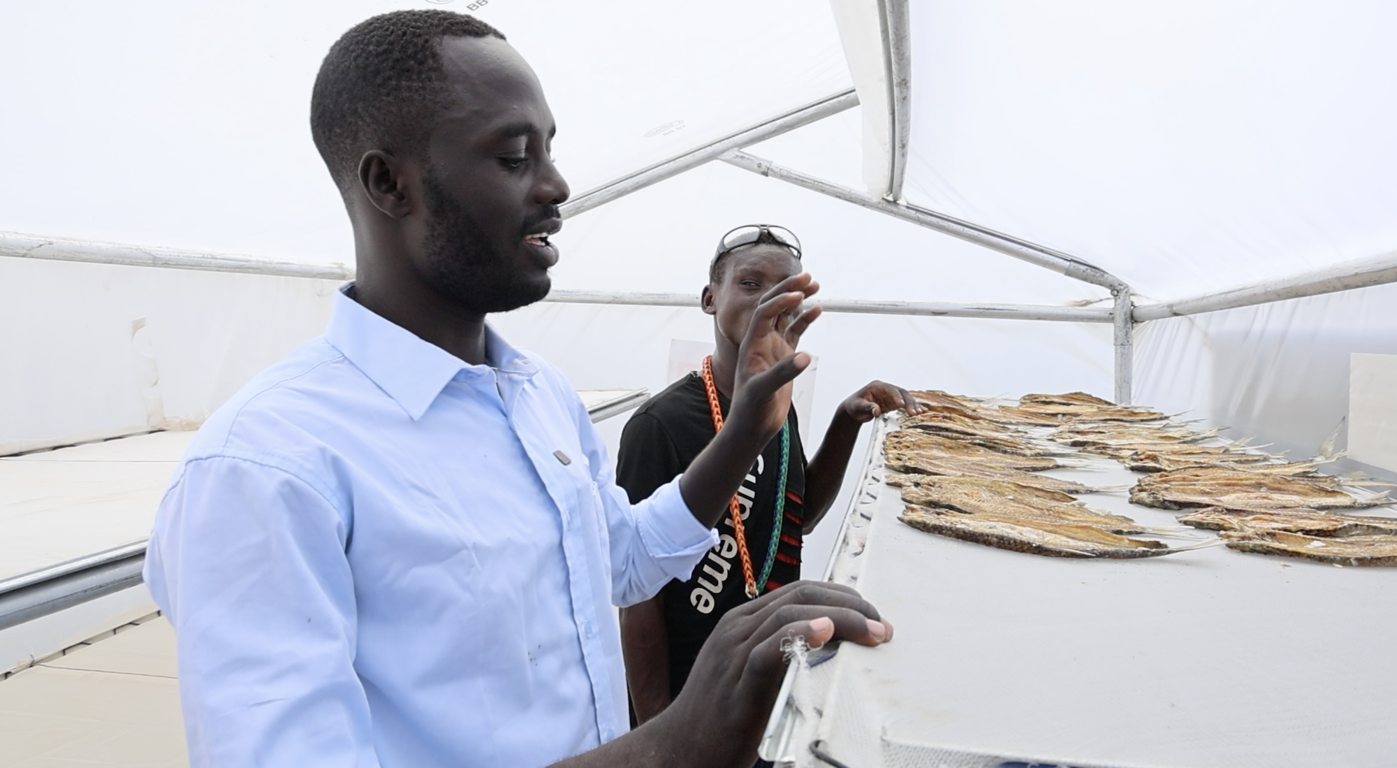 Gabriel Mujibi (in sky blue shirt), the Fisheries Officer, Kenya Fisheries Services in Loiyalangalani Sub-County explains how the fish dryers work in preserving and drying the fresh catch from the lake.