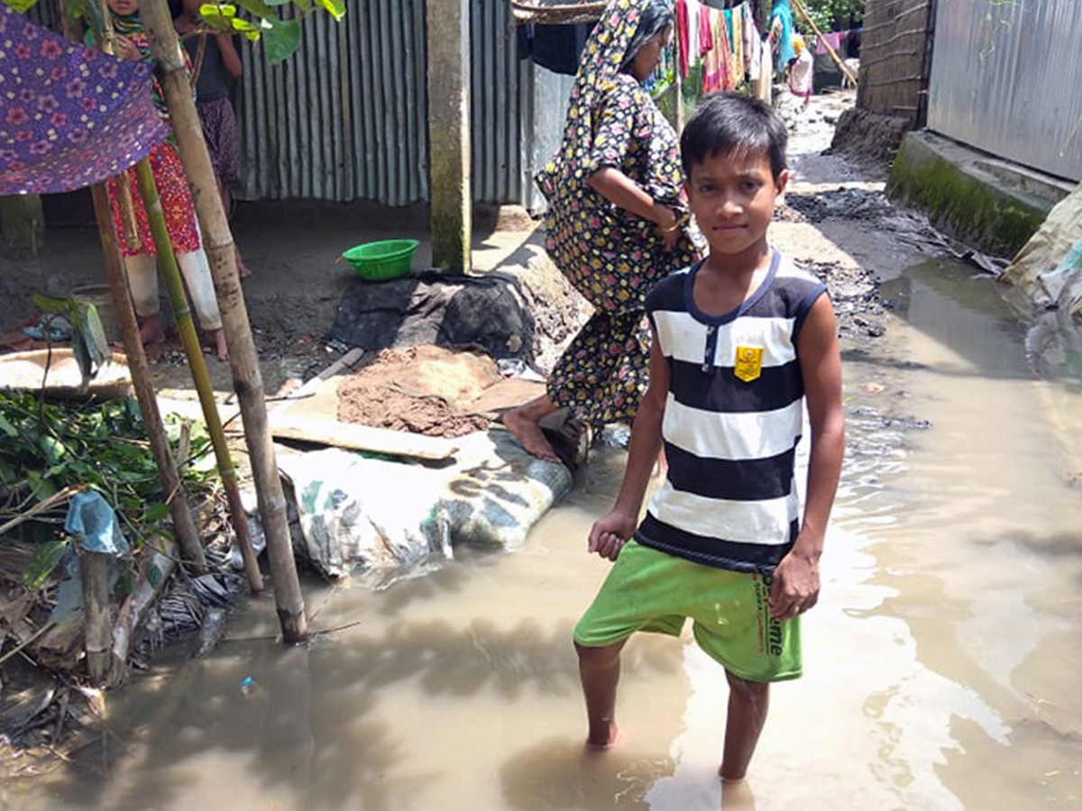 Kibria (10), sponsored child of World Vision Bangladesh standing on the water in their yard