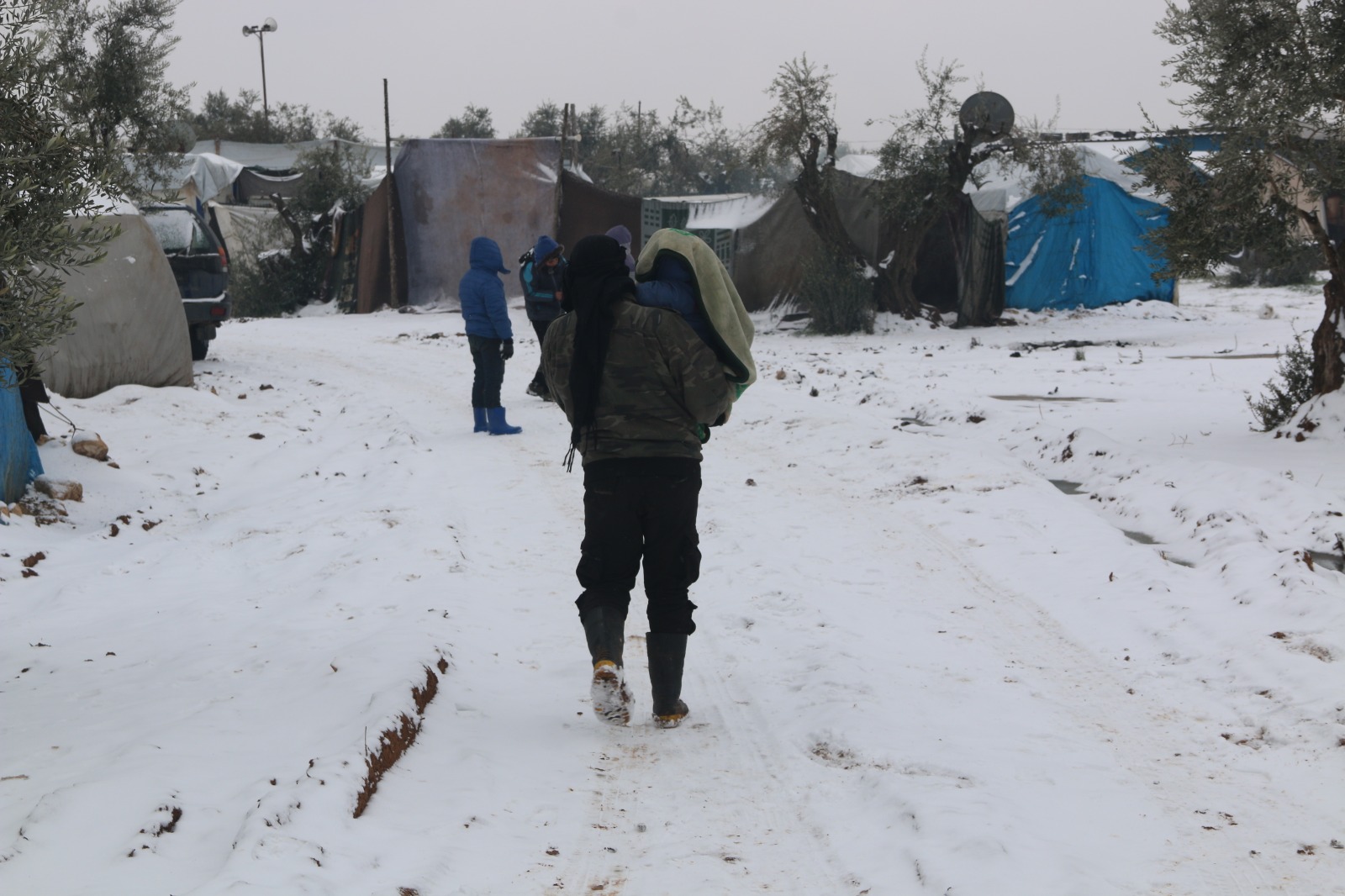 Displaced Syrian families in an informal displacement camp covered in snow.