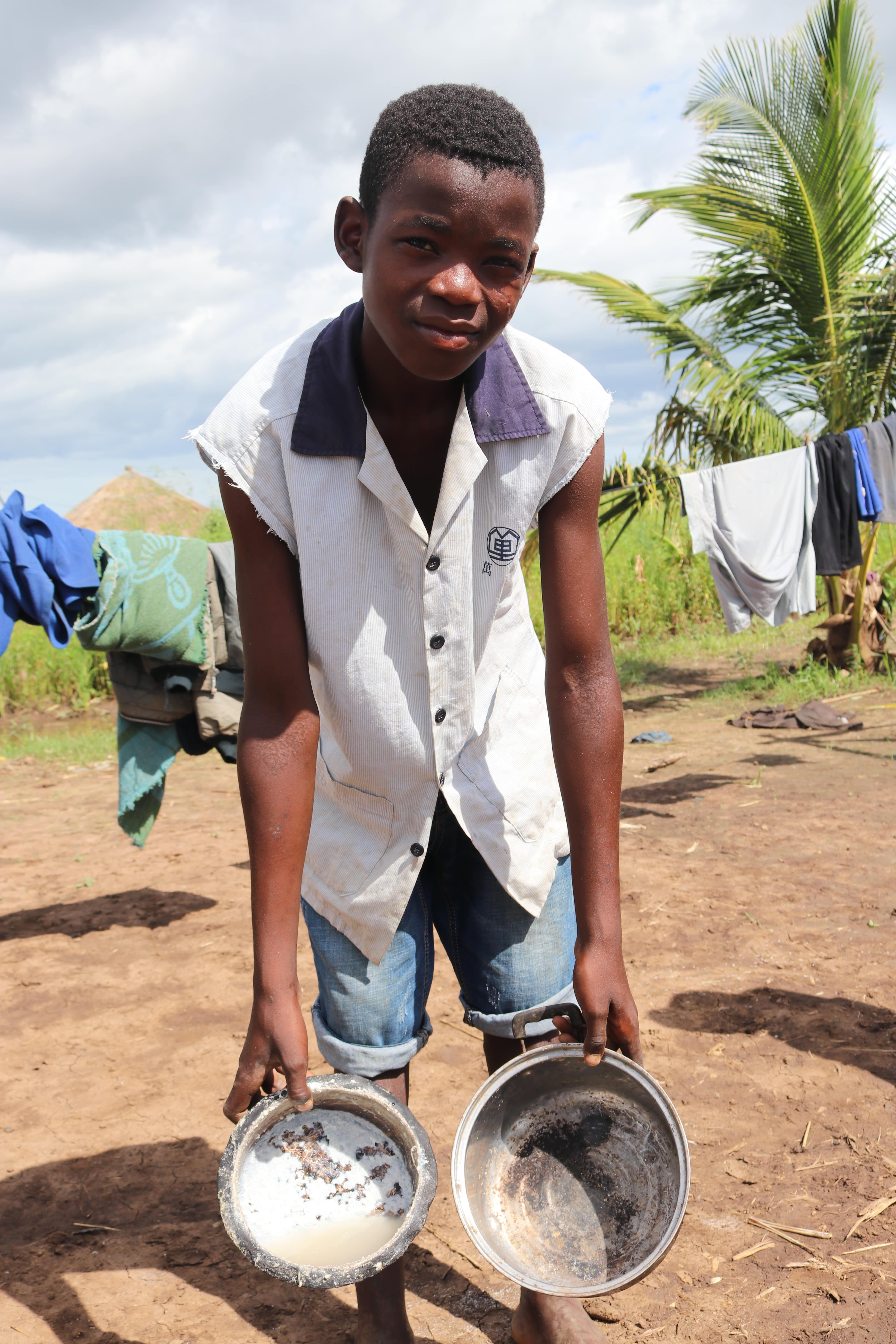 Tiago showing the small pots they use to cook their meals. On the day of the interview, they had only one meal.