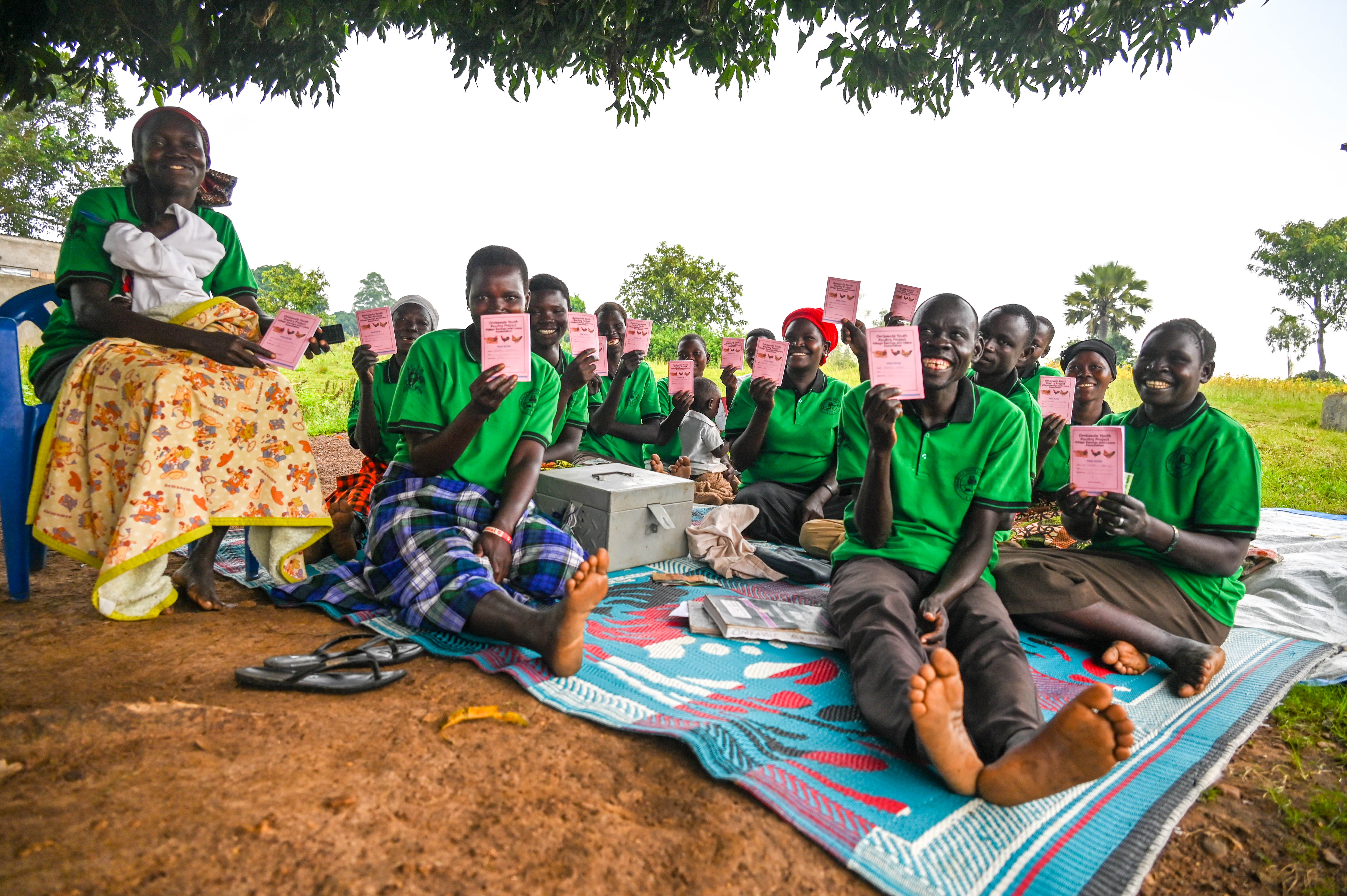 Stella (center) with other members of Obabule Saving and Loan group diplaying their saving booklets 