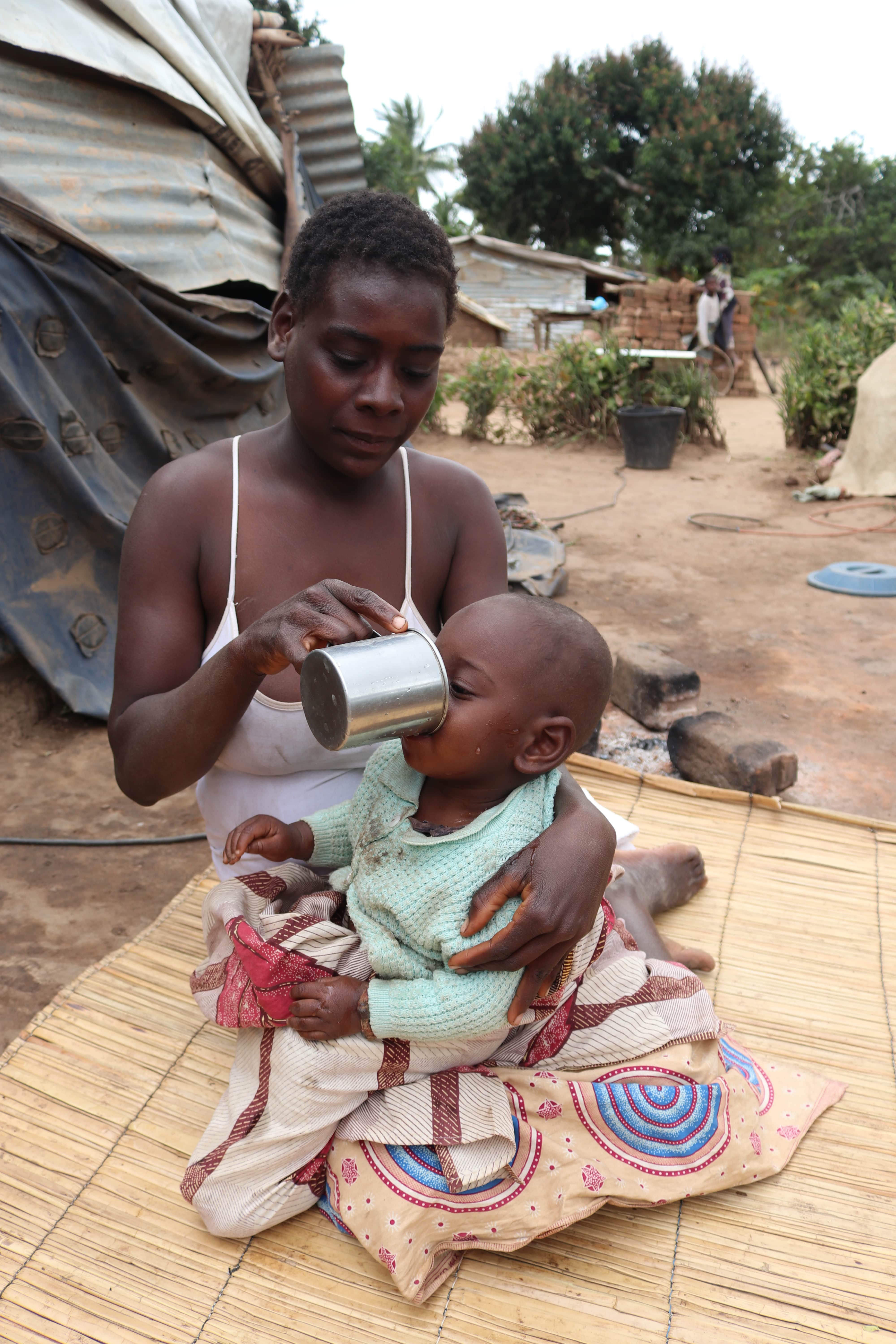 Amélia is feeding her little boy Helton with a milk