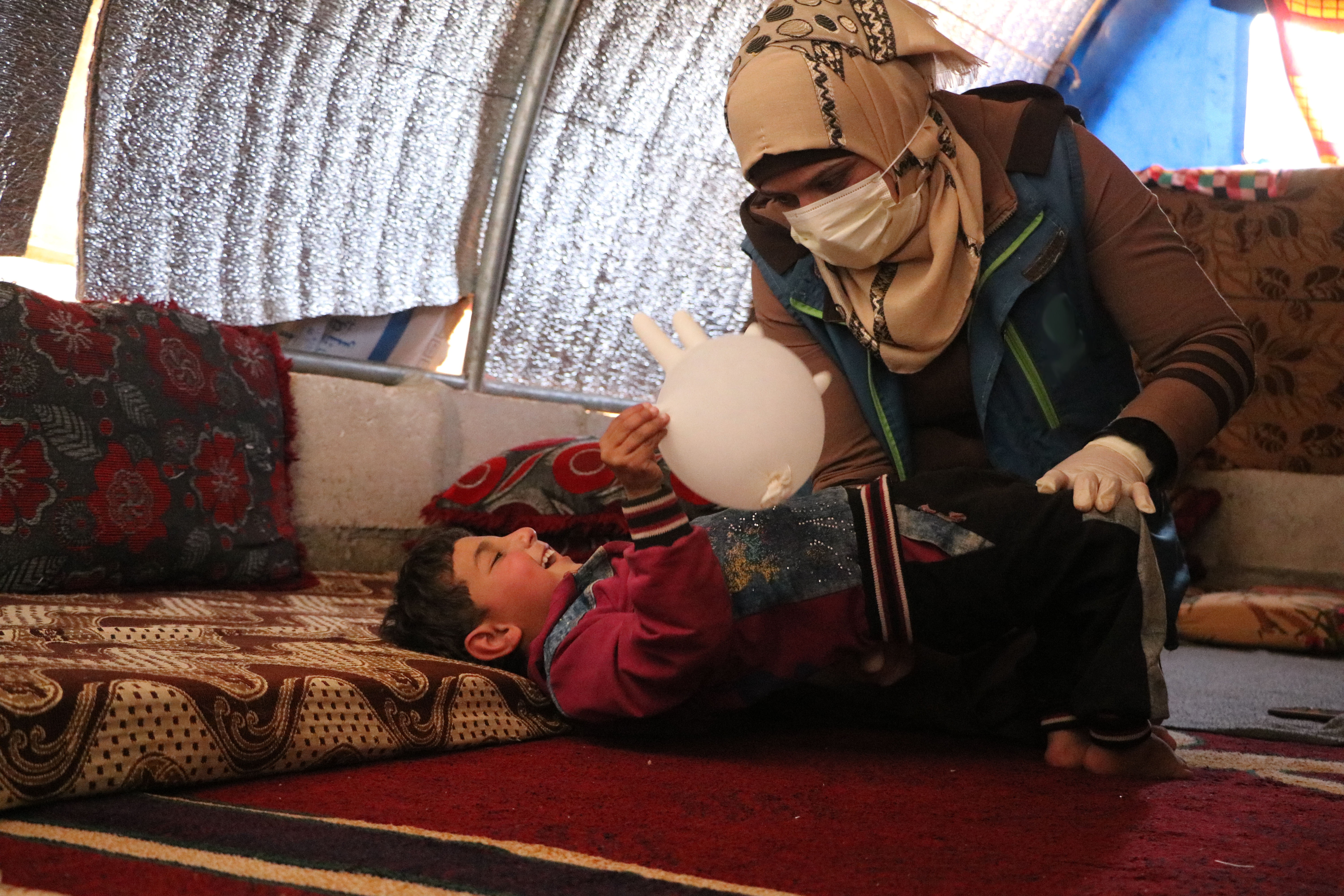 A physiotherapist at a young female’s tent conducting rehabilitation training with her son.