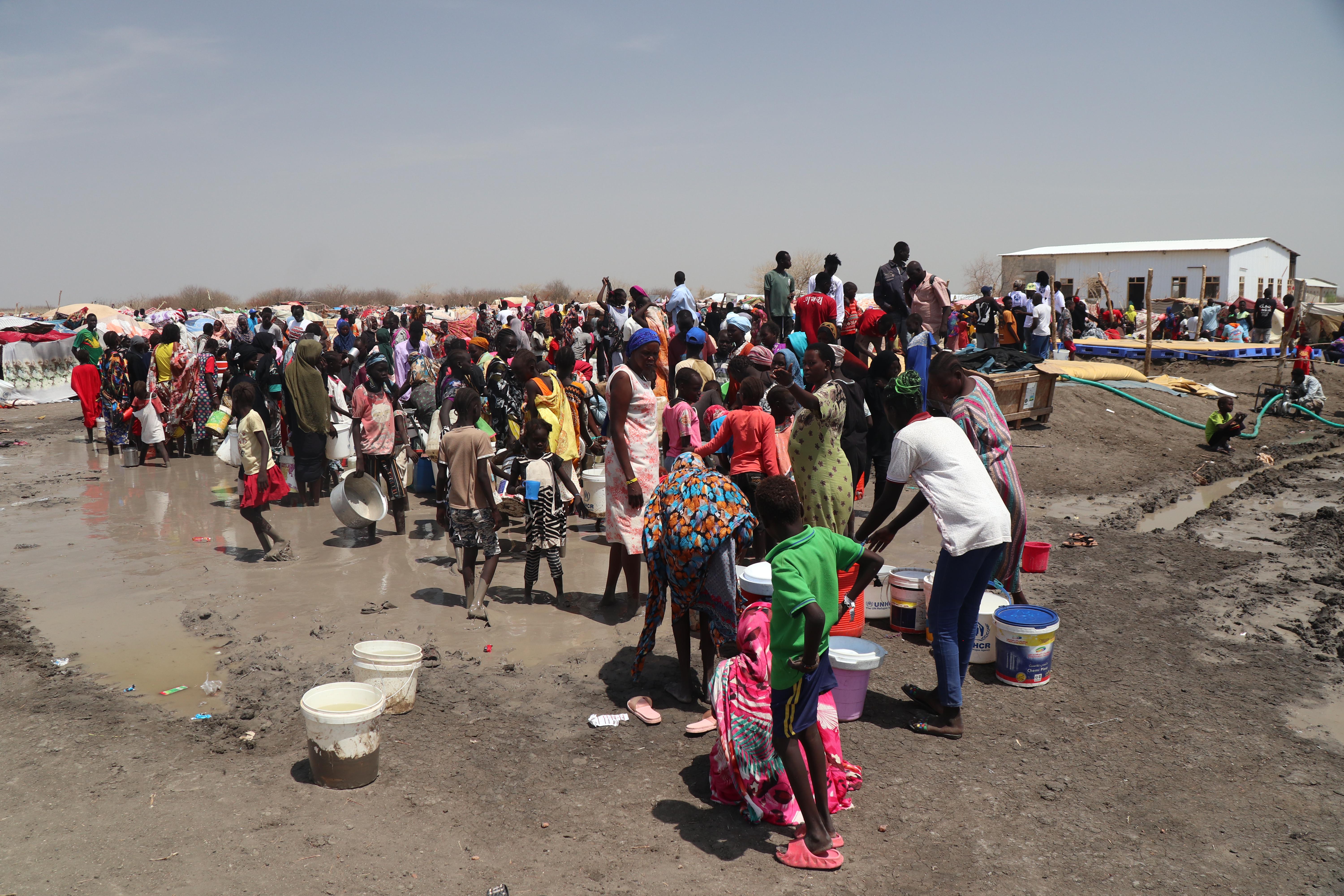 Refugees and returnees fetch water from a nearby water source. 