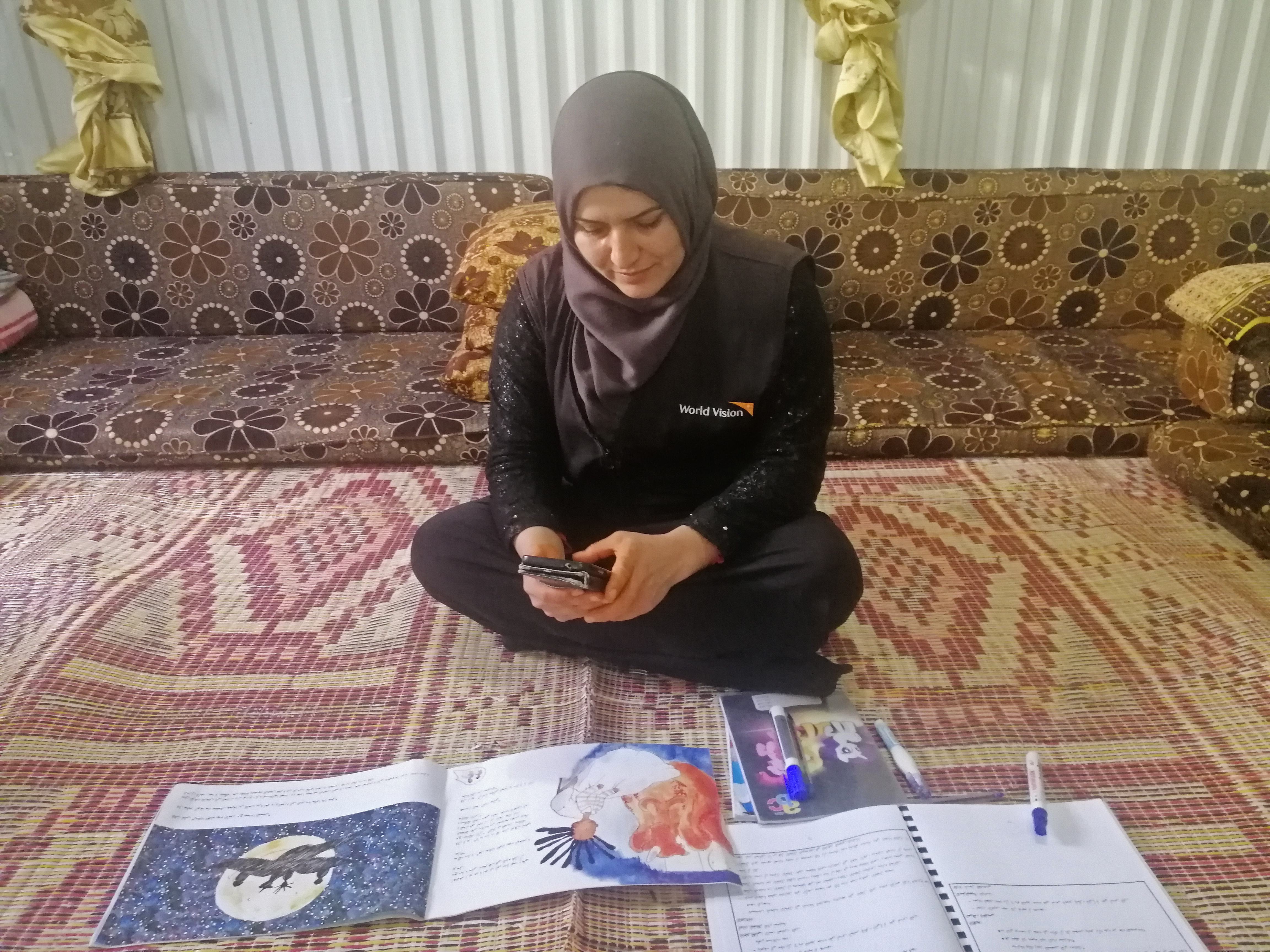 Fatima, a teaching assistant at our ECD programme in Azraq Refugee Camp is taking photos of the book before she sends to the students