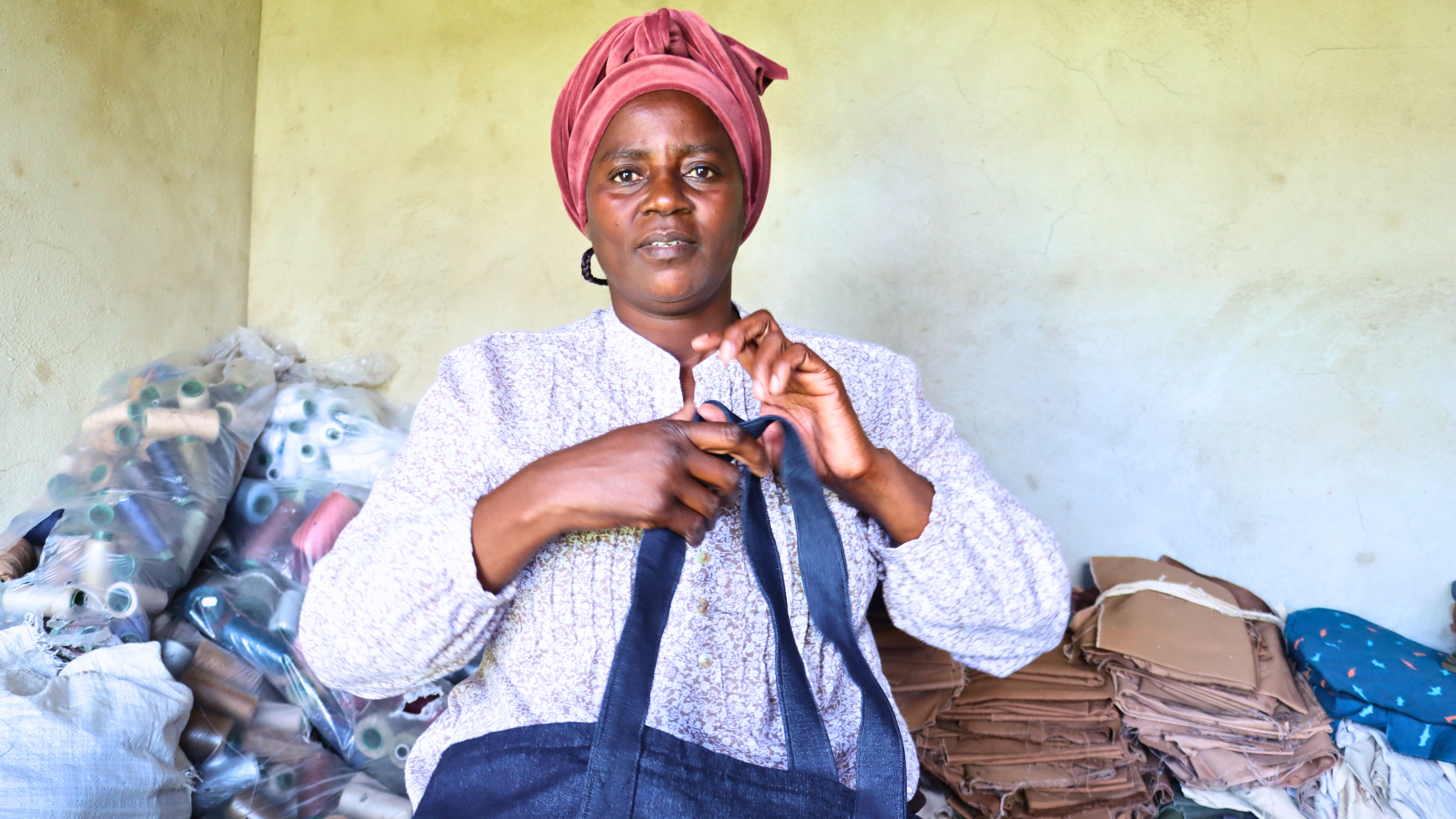 Nonhlanhla holding one of the bags she sewed with fabric she bought after borrowing money from her savings group.