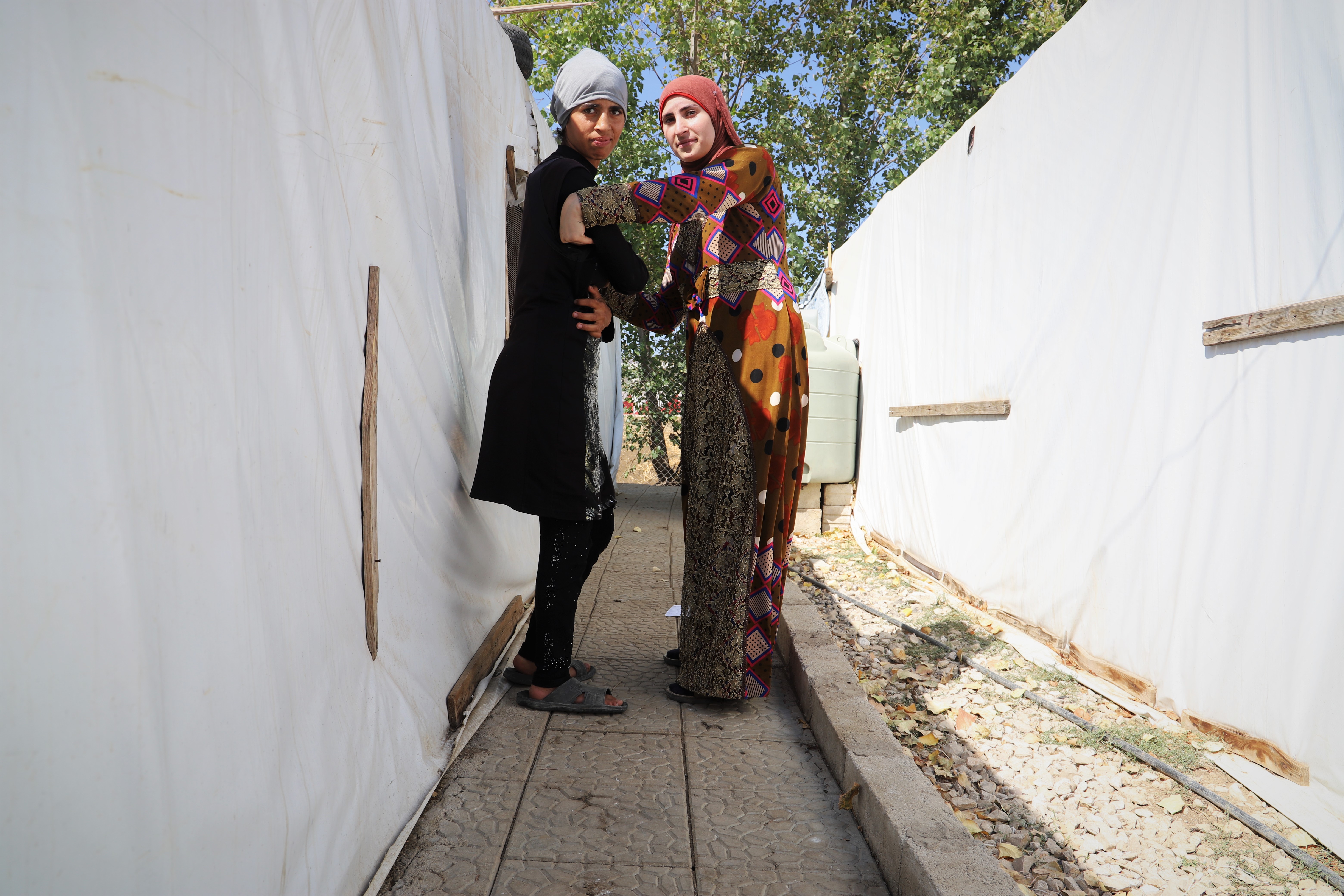 Halloum helping her sister Ghaziie go to the latrine