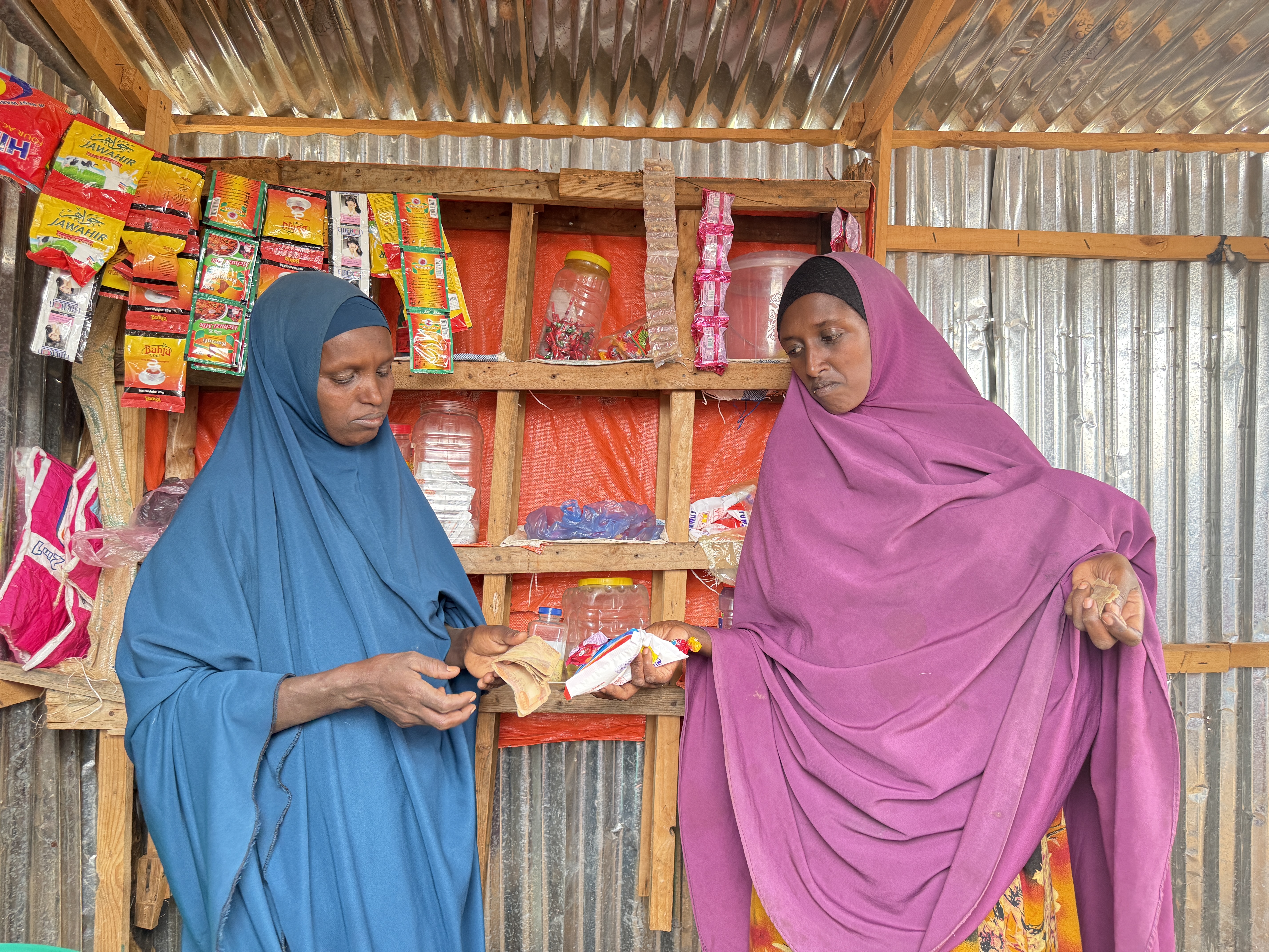 Nishey in her small neighbourhoods shop, selling something one of her  customers.