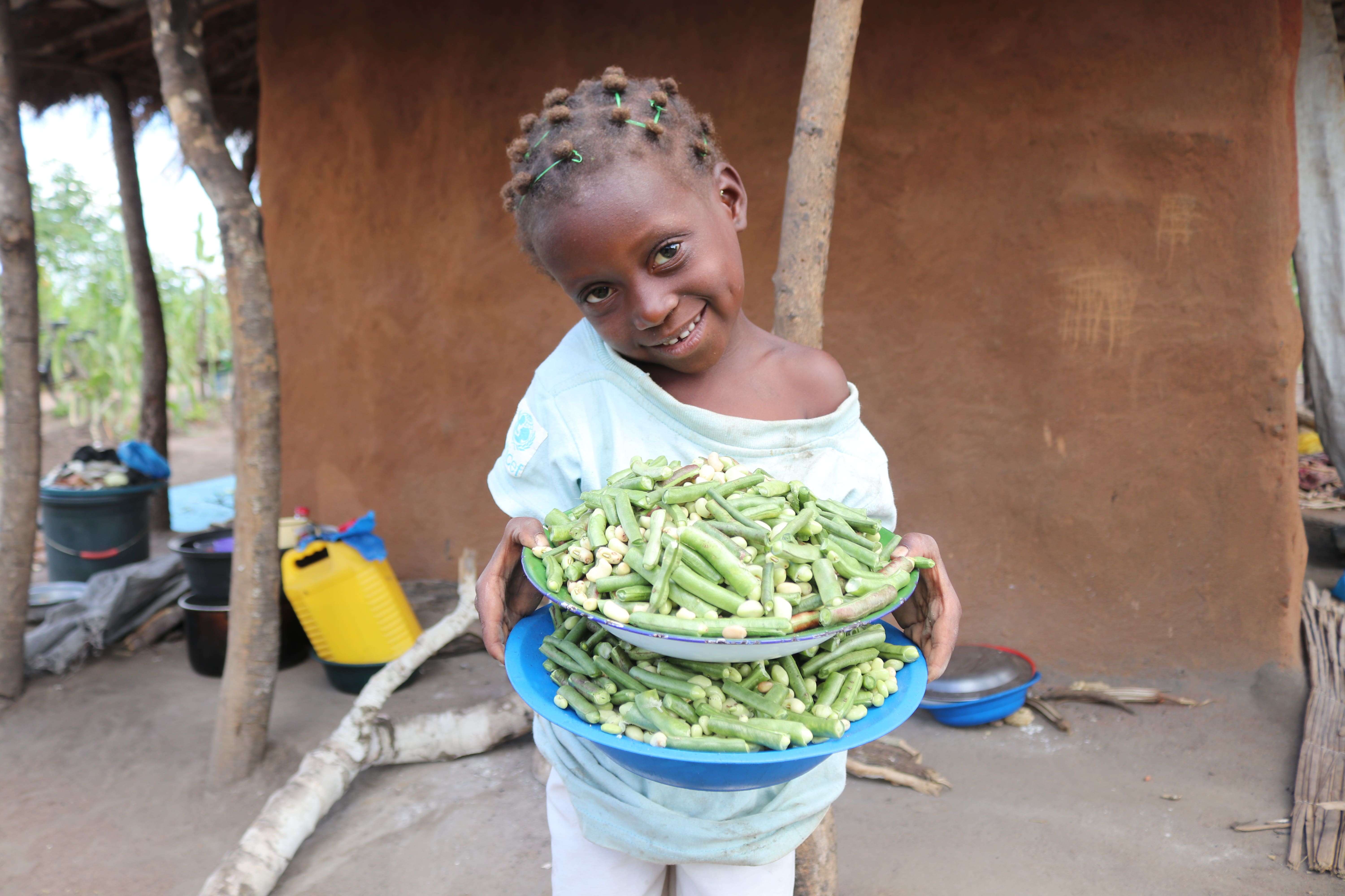 Rosa holds a plate of beans after her grandma Luisa harvesting from kitchen garden