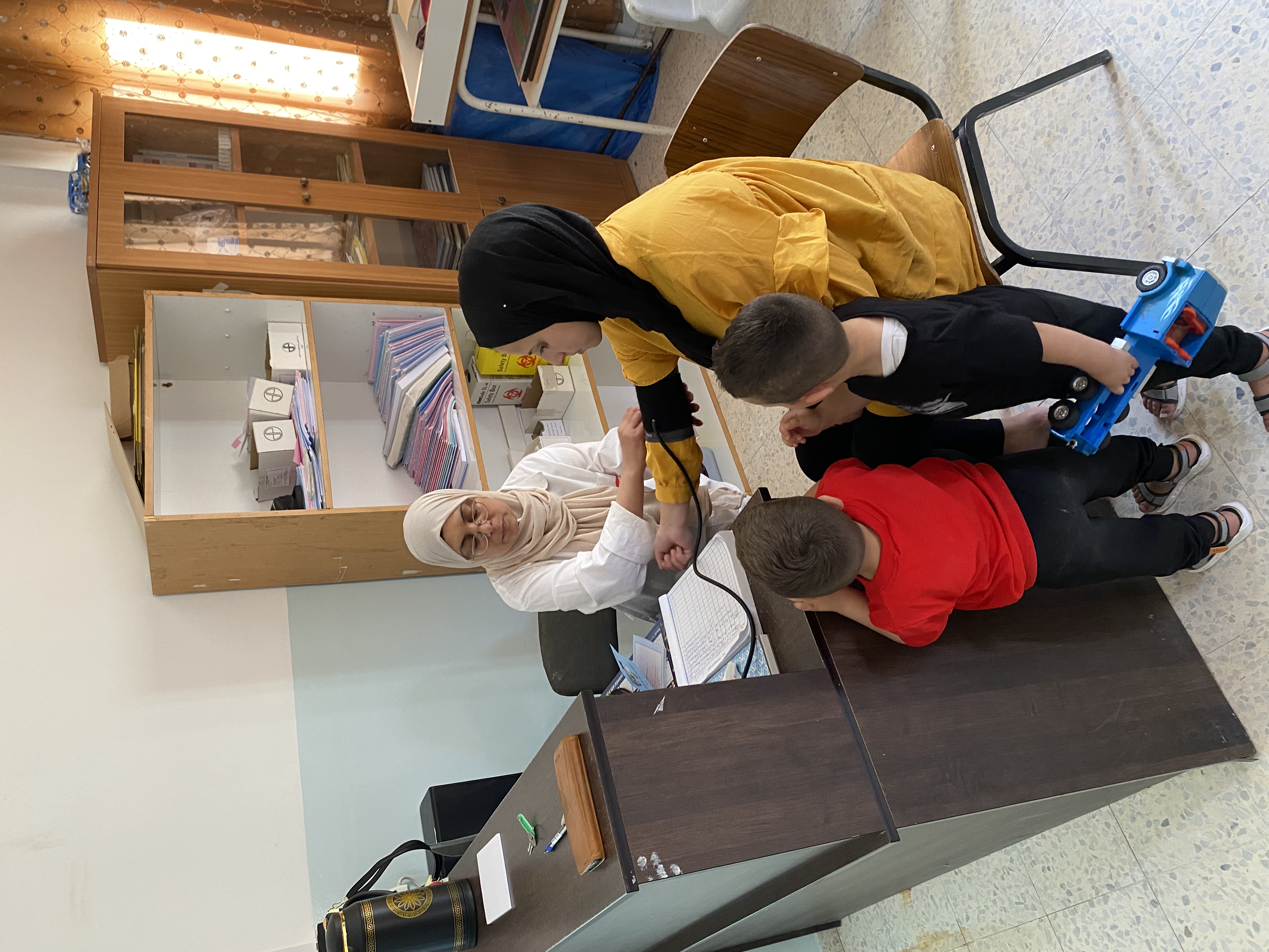 A doctor is providing care to a mother in a clinic supported by World Vision in the south of the West Bank