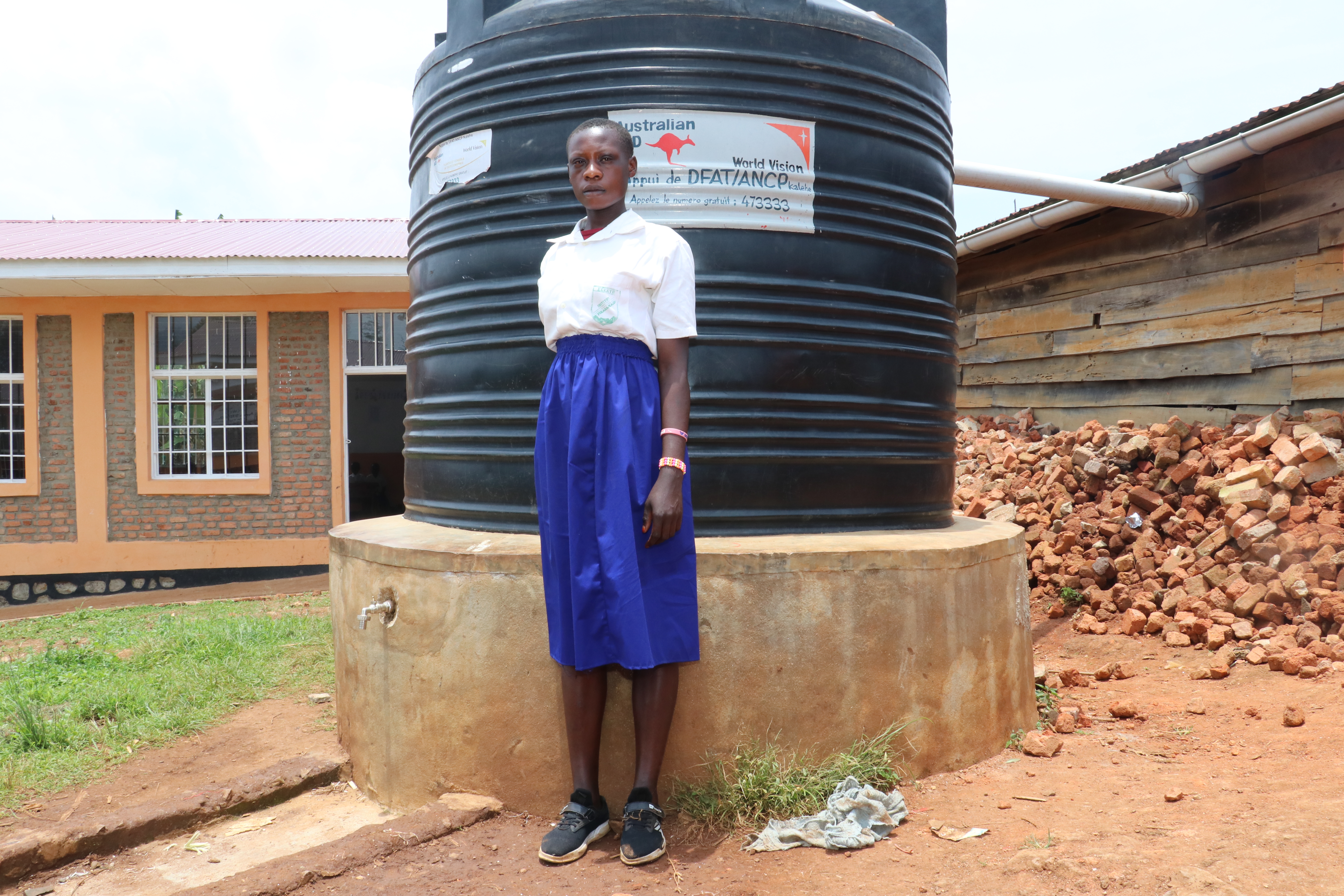 Vanessa in front of a water tank built by World Vision