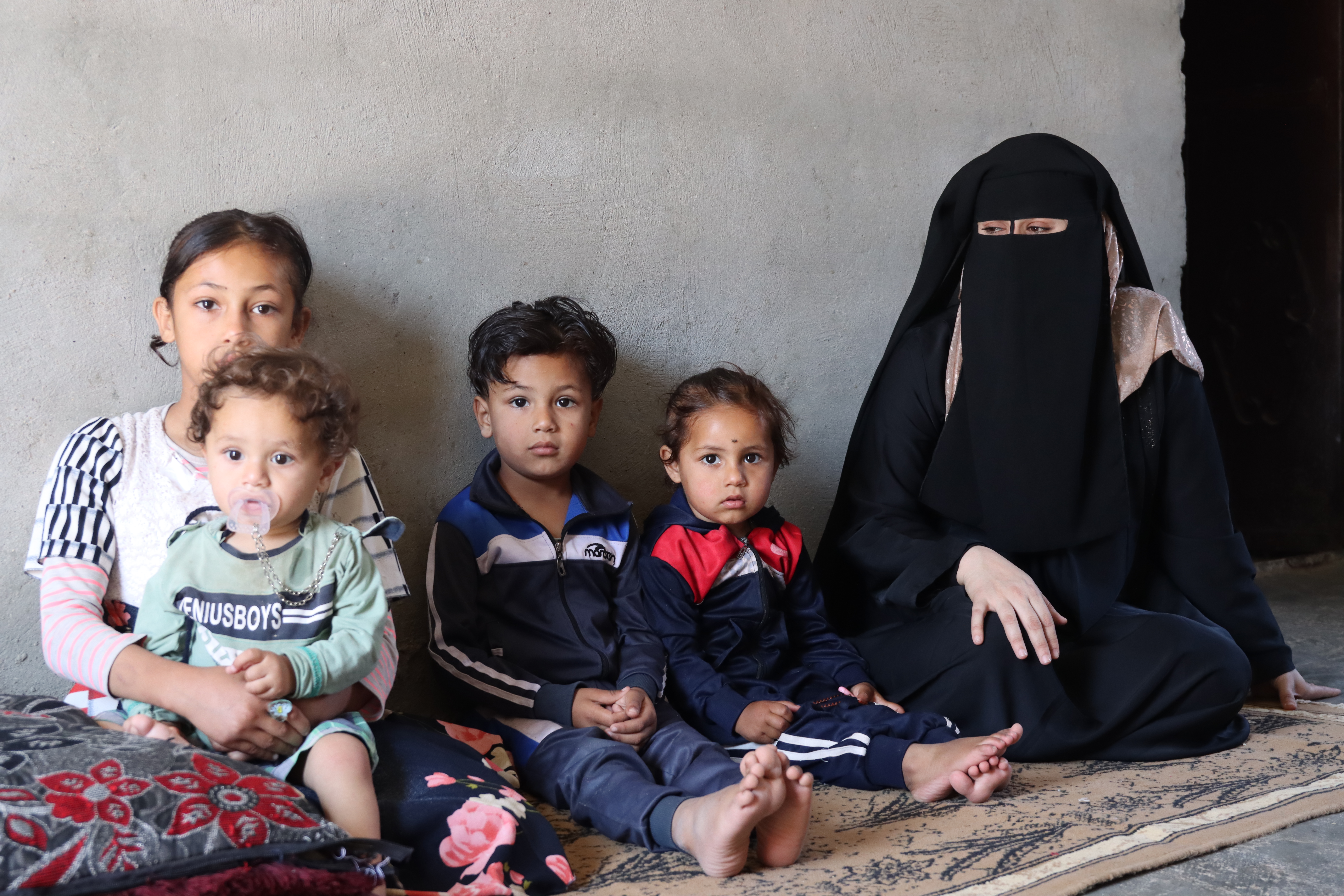 Khloud sitting in her home with her children