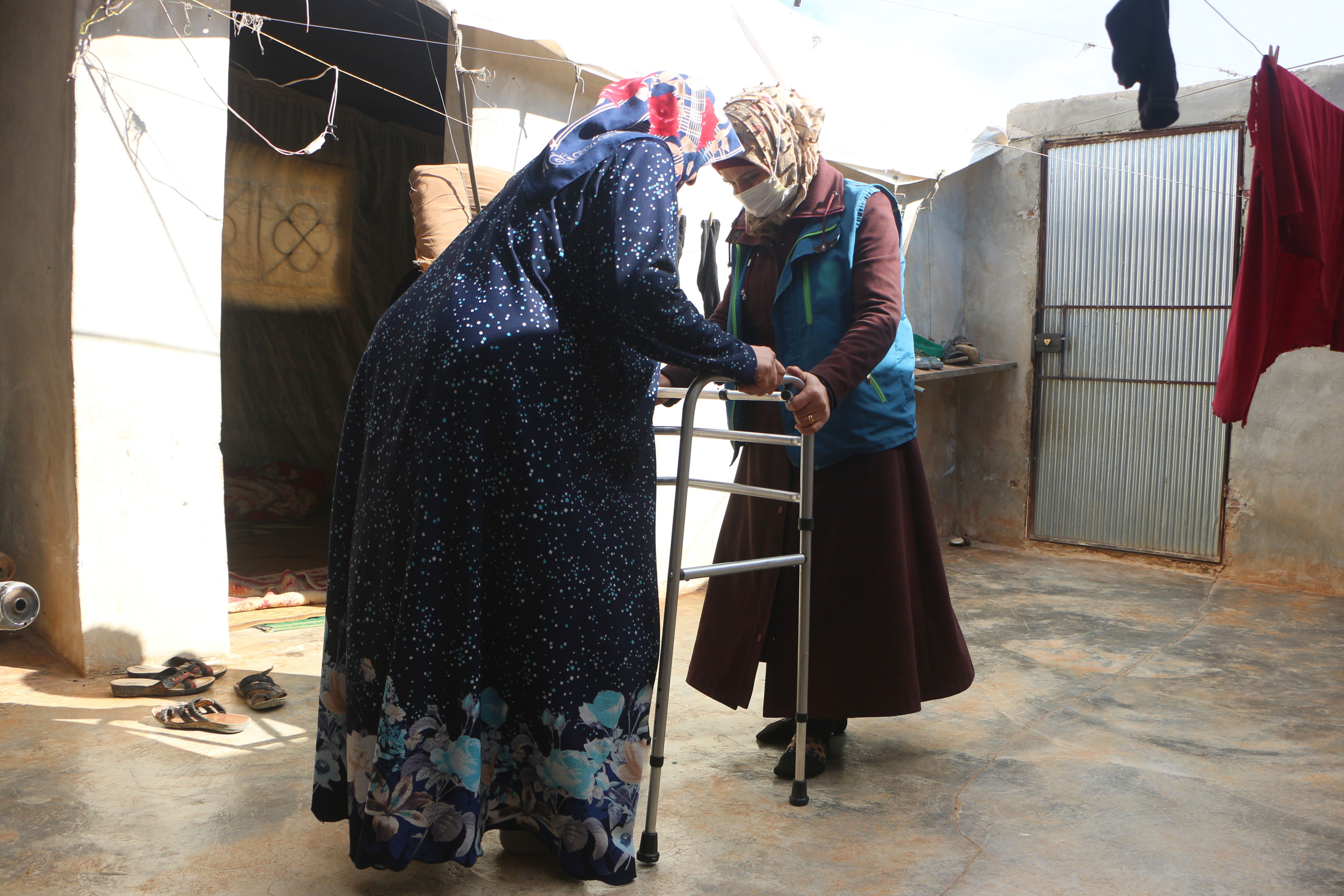 An old woman received a walker and she was trained by a physiotherapist on how to use it. 
