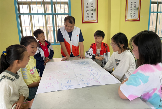 Jay, 3rd from the left, participates in a group discussion with other children and draws their dream village.