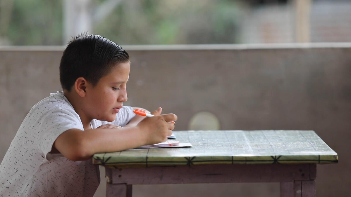 Joshua, sponsored child in Ecuador writes at his home .