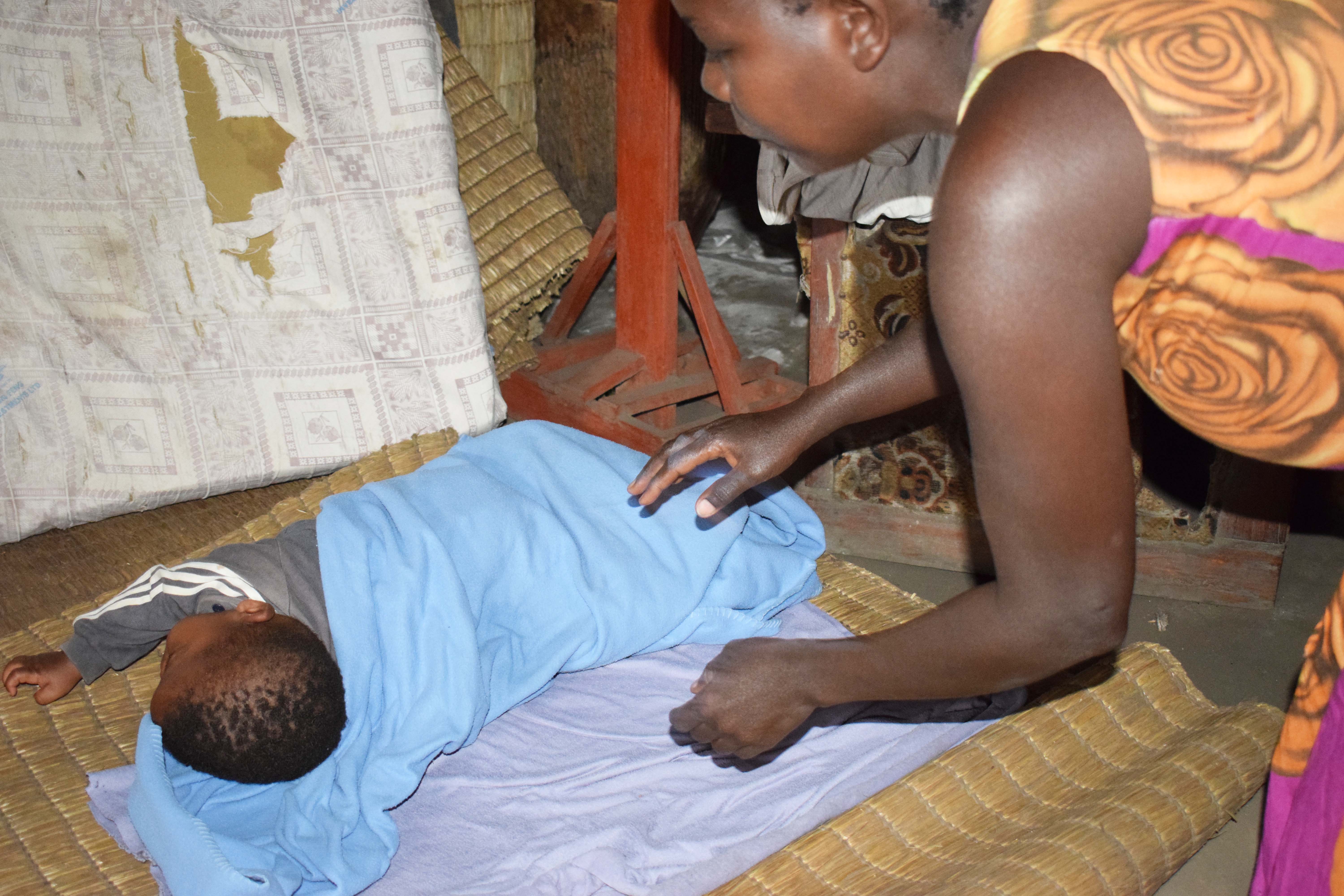 Joy, laying her 6-months-old girl on a mat. The mat is on the dusty pulpit of the church. copy