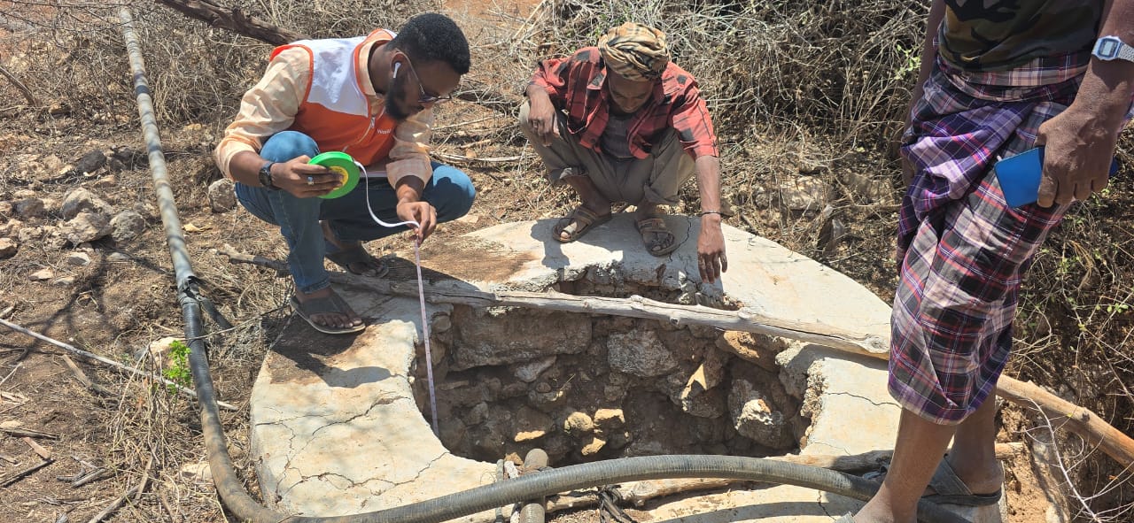 Muktar Hassan, NAF Project Officer, measuring the depth of an uncovered shallow well on Ibrahim’s farm in Hudur district, Somalia, March 2025. The surrounding area appears dry, underscoring the urgent need for rehabilitation to support effective farm irrigation.
