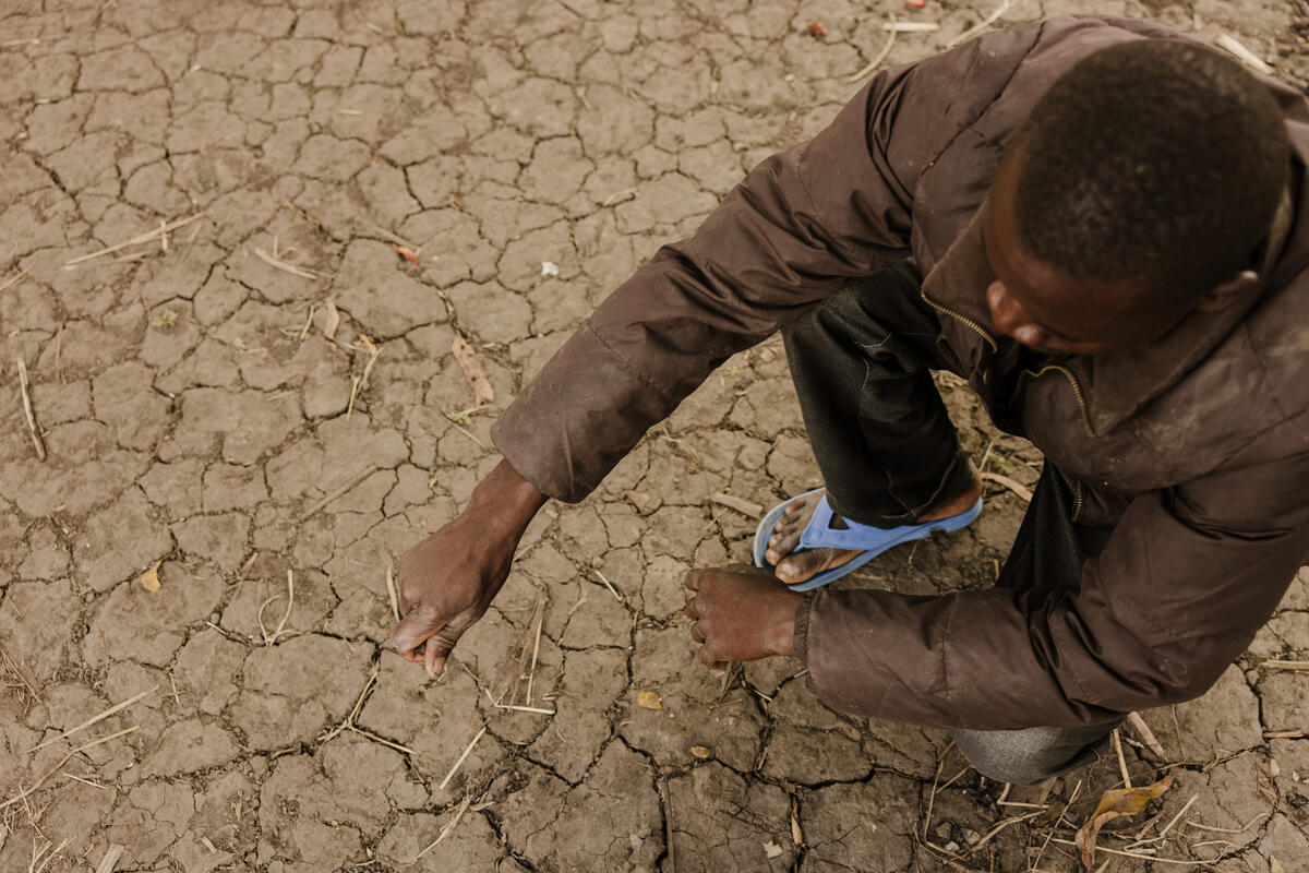 Father in Malawi looks at parched land that destroyed his crops