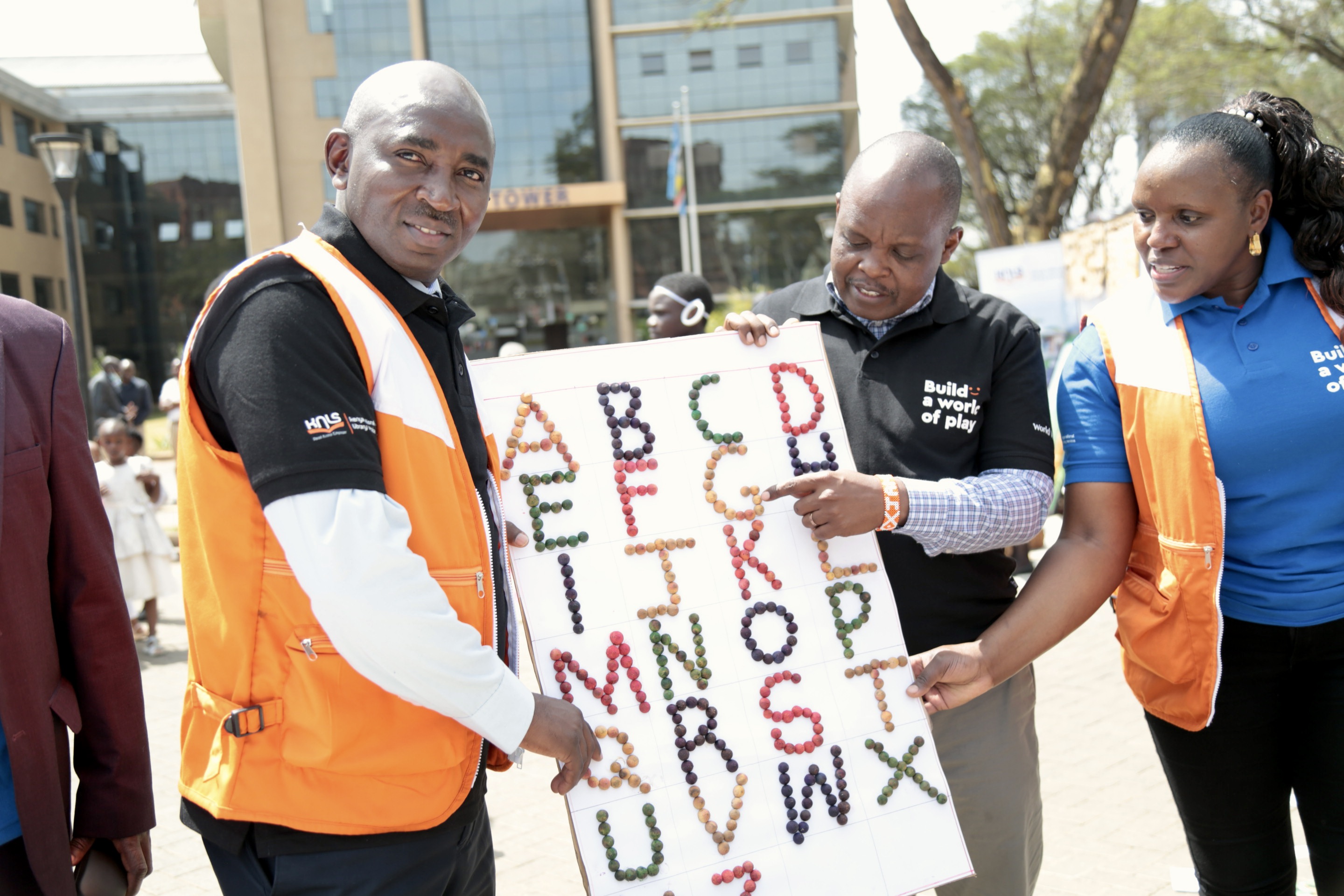 World Vision Ag National Director Geoffrey Kativa with colleagues pose with local play and learn materials