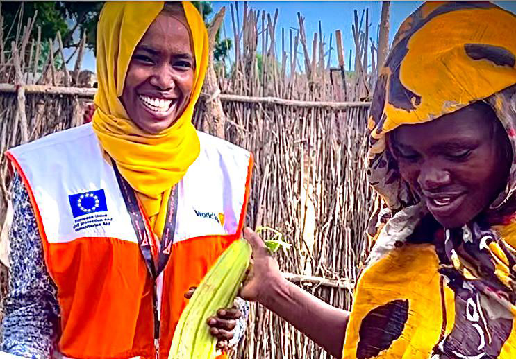 Mary proudly guides a World Vision staff through her flourishing kitchen garden.