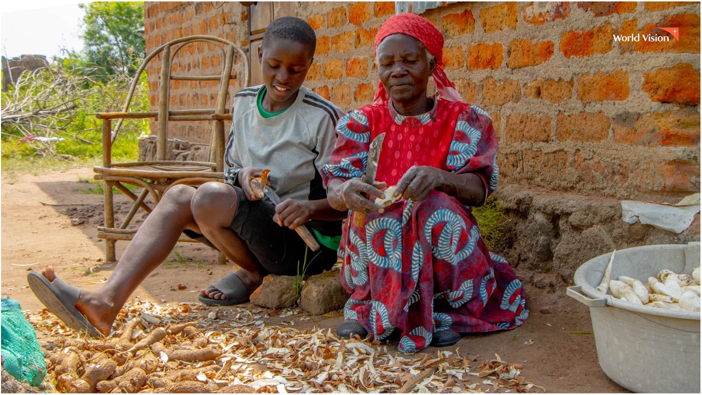 Kate and her grandmother are preparing cassava for their lunch. On their farm, they have planted cassava while nurturing indigenous and fruit trees, which also provide a habitat for beekeeping.