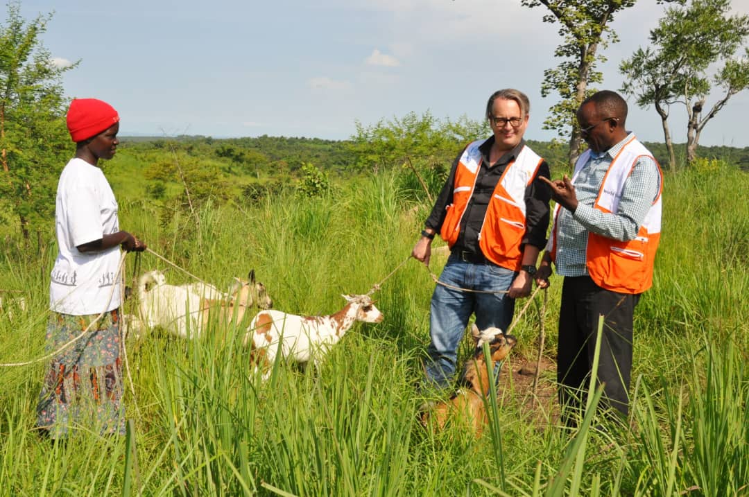 World Vision Uganda National Director, Jason Evans, Board member Dr. Micheal Kansiime interacting with one of the beneficiary of the goats project in Omugo.