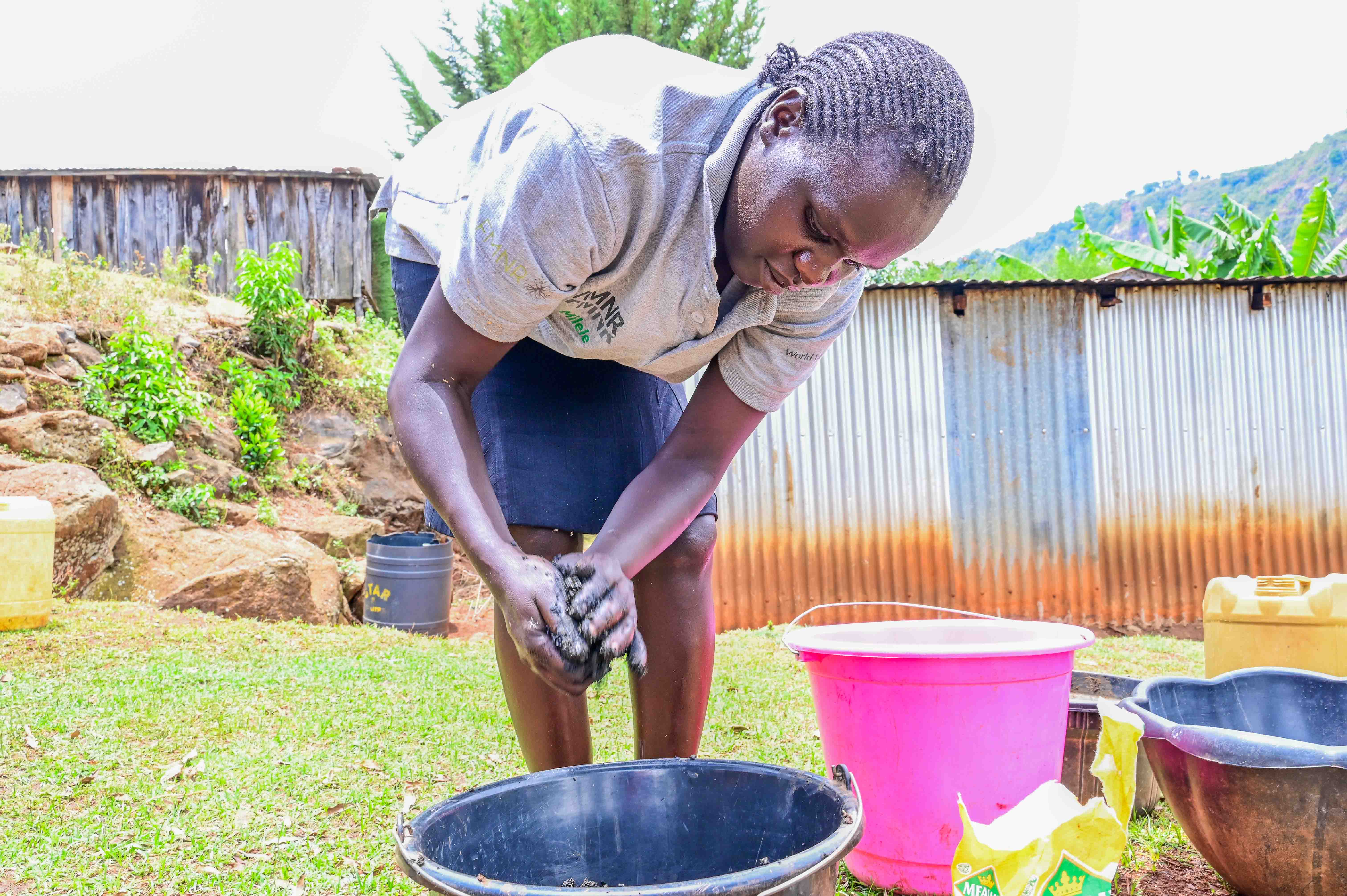 Sophia moulds the mixture consisting of cow dung and ash to form circular briquettes. ©World Vision Photo/ Hellen Owuor