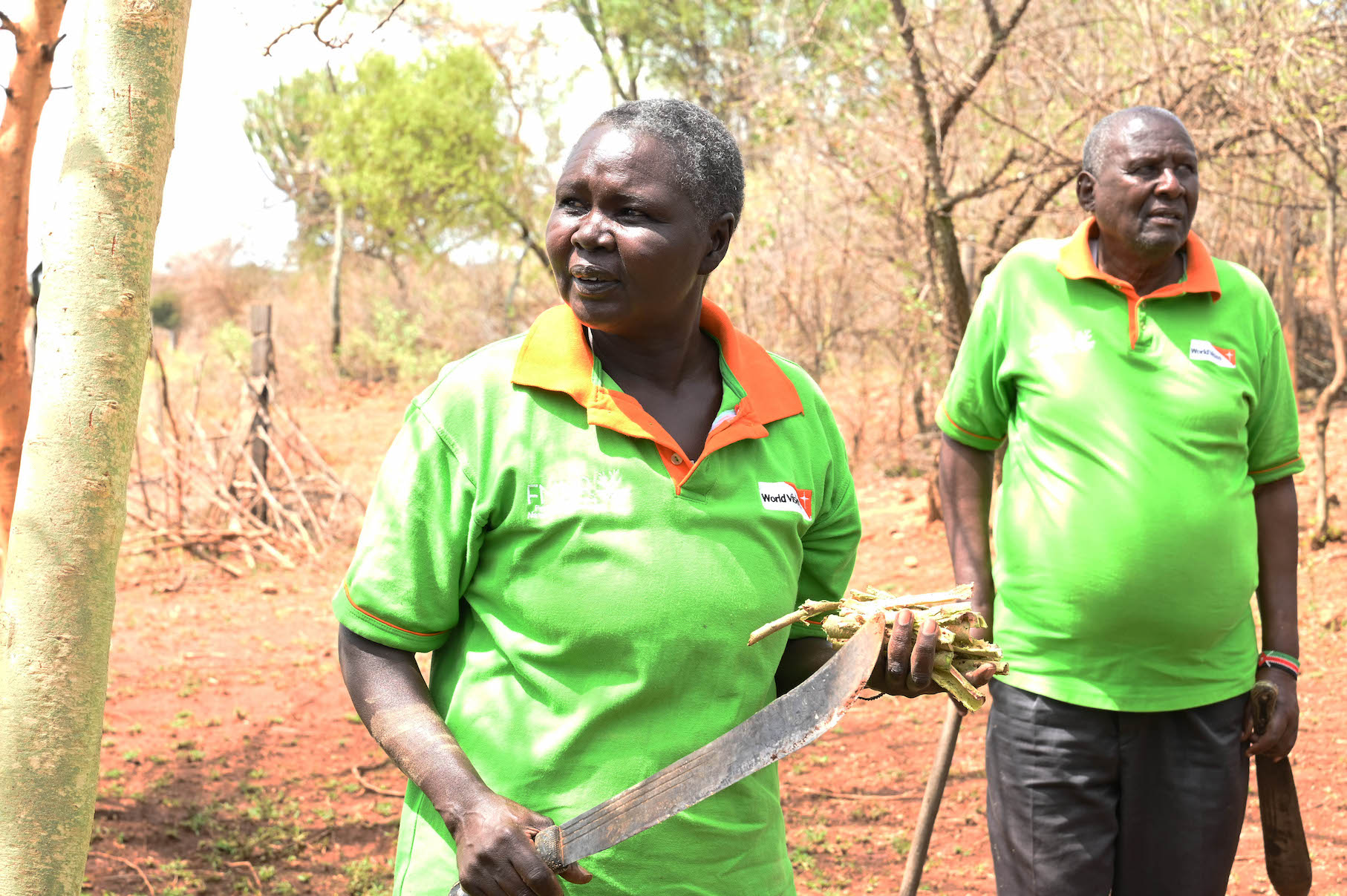 Nancy usually pounds pruned branches using a stone  to peel their barks. These peelings (in her left hand) are used as animal feed while the peeled branches are used as firewood. ©World Vision Photo/Hellen Owuor.