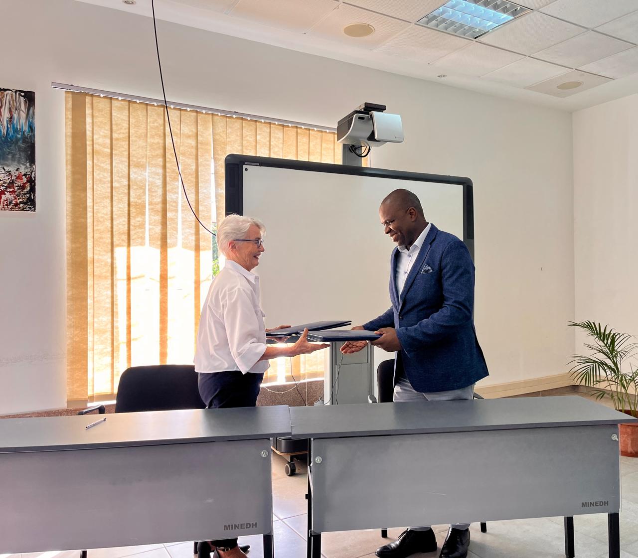 Henny Matos (on the left) exchange folder with the Andre Massabo after signing the Mou.
