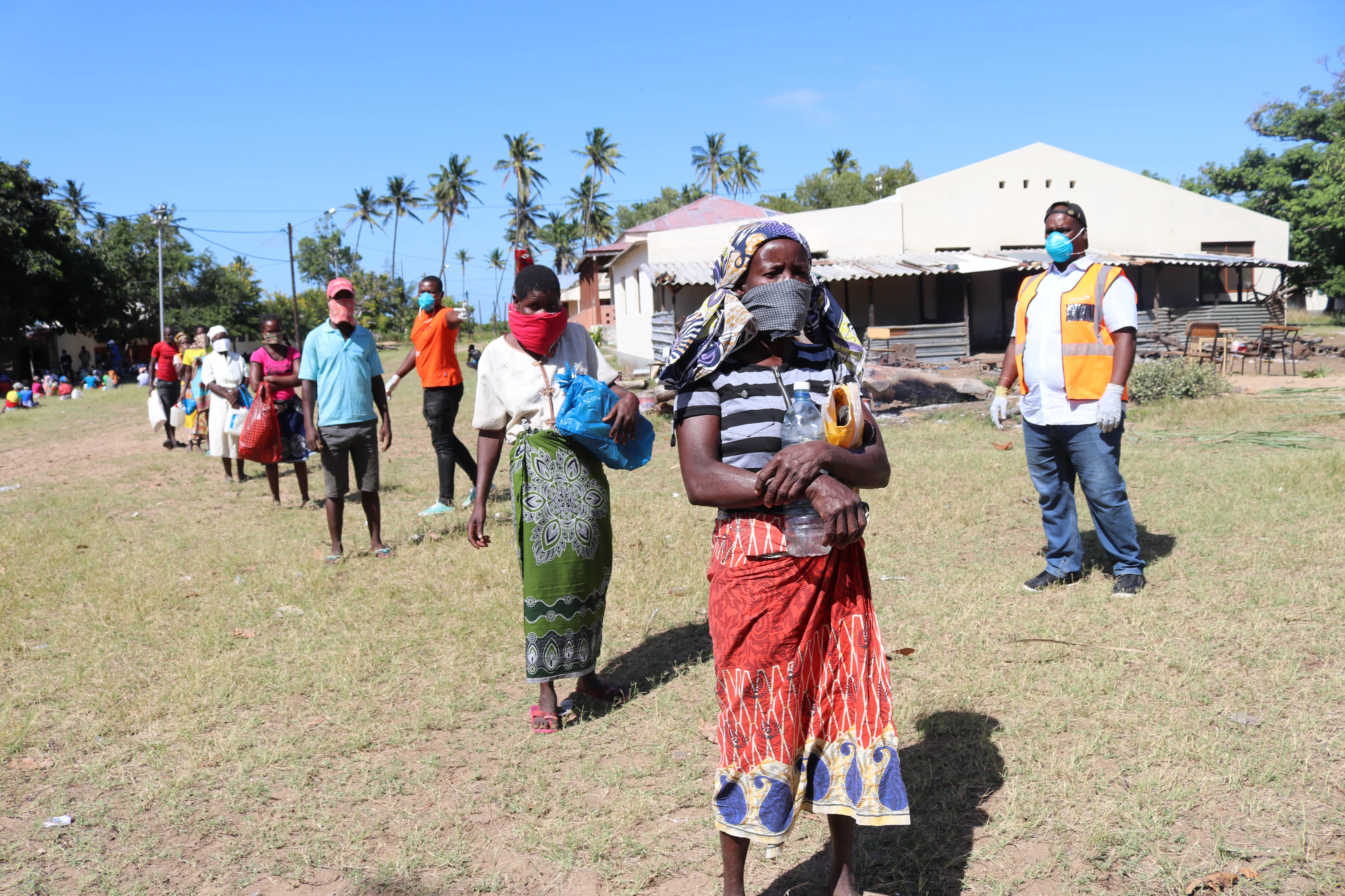 Beneficiaries wait to receive their food at a food distribution site