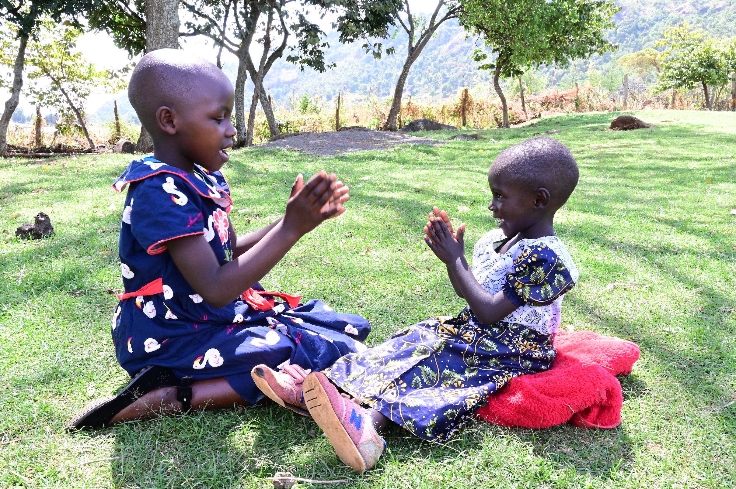 Lazarus’ daughter, Anneth aged 9 (left) and his granddaughter Velmur aged 4 (right) are shielded from the scorching sun as they play under the tree shade. ©World Vision photo/Hellen Owuor.