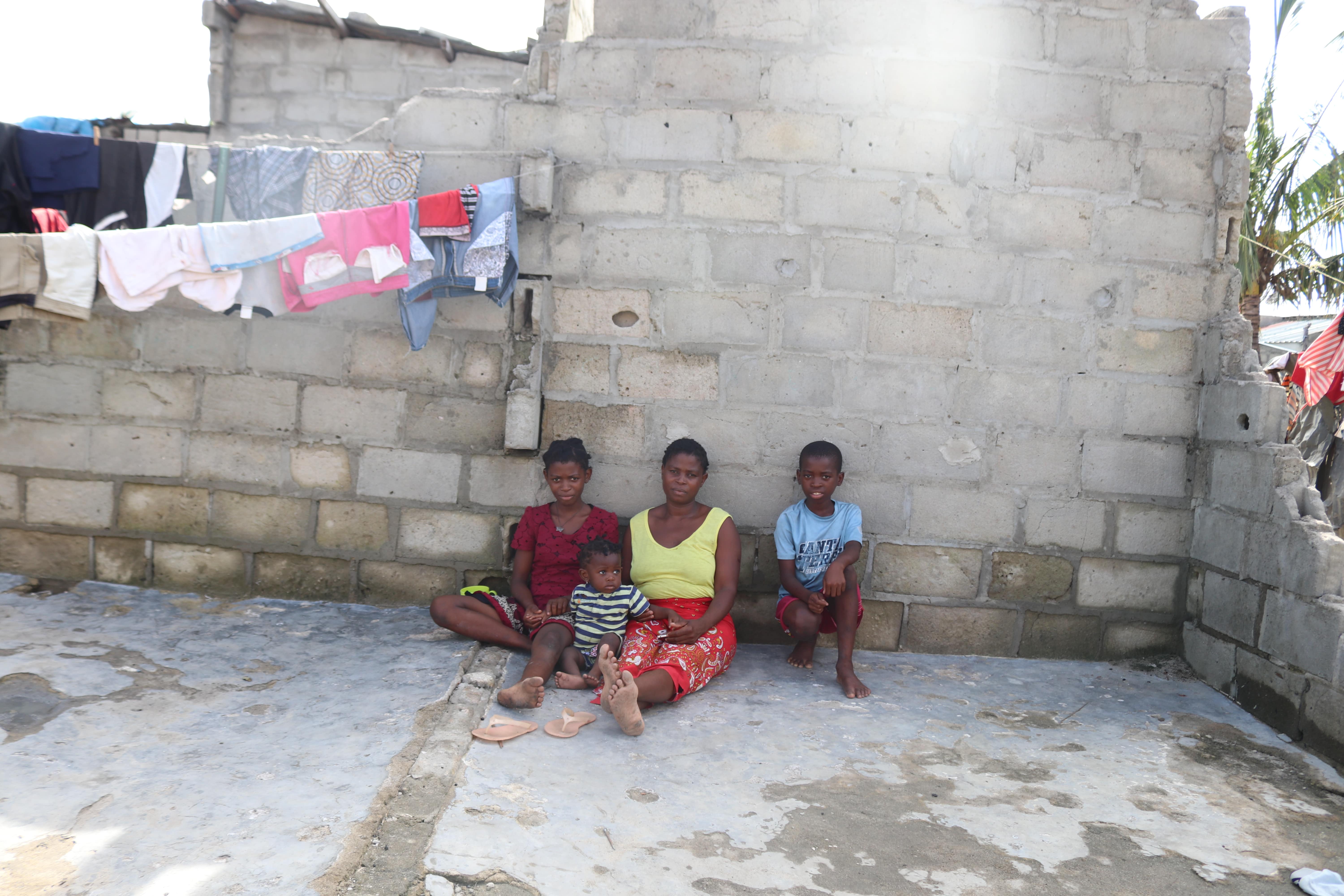 Deocina sitting with her three children on the floor of a part of their house that resisted Cyclone Eloise 