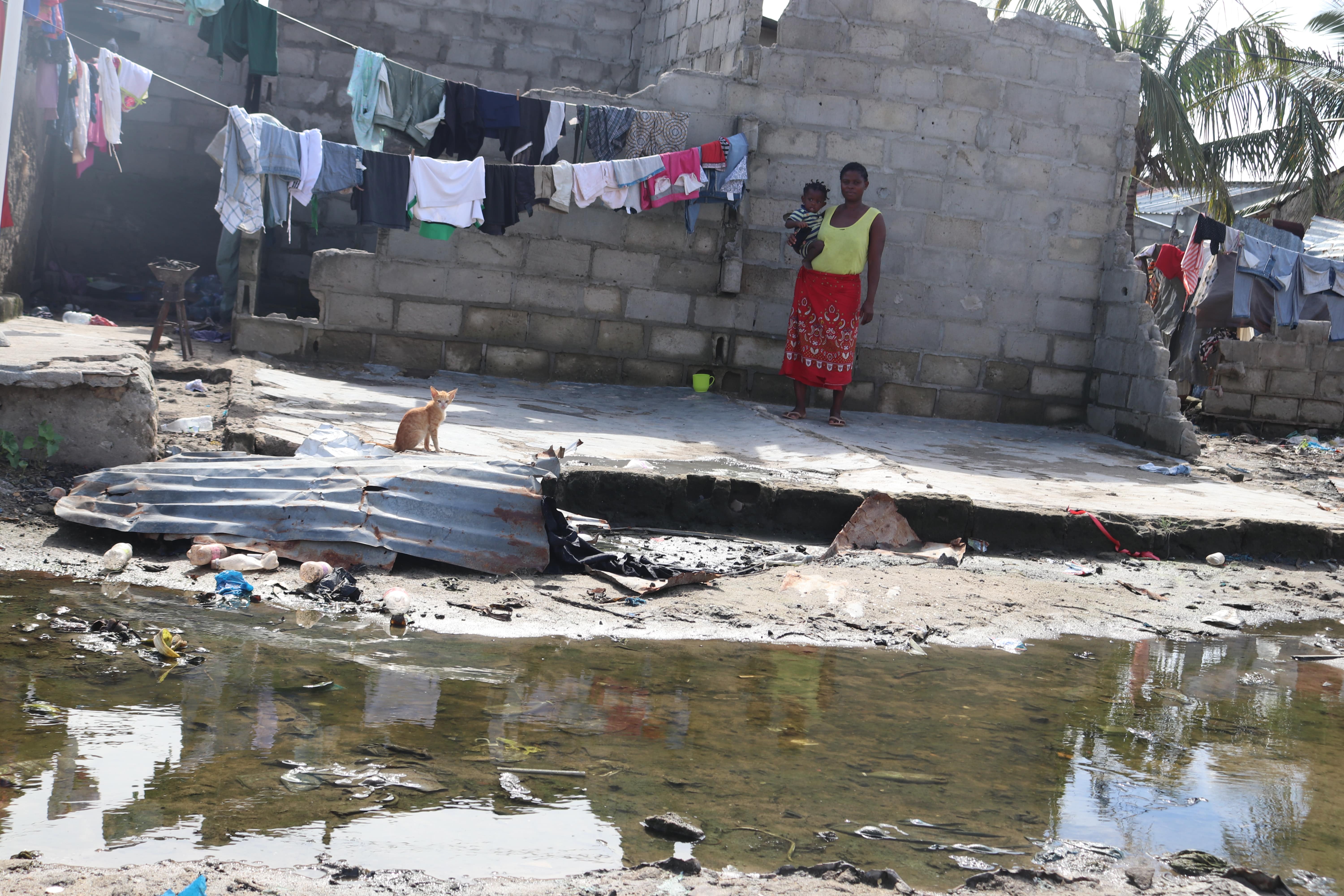 Deocina with her new birth are standing in front of the wall that resisted in her house following the landfall of Cyclone Eloise,  