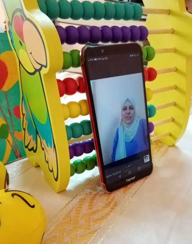 Safaa is recording herself explaining today’s lesson to the students. The teacher is using any type of equipment she has at home to ensure the best video experience for children during the classes. 