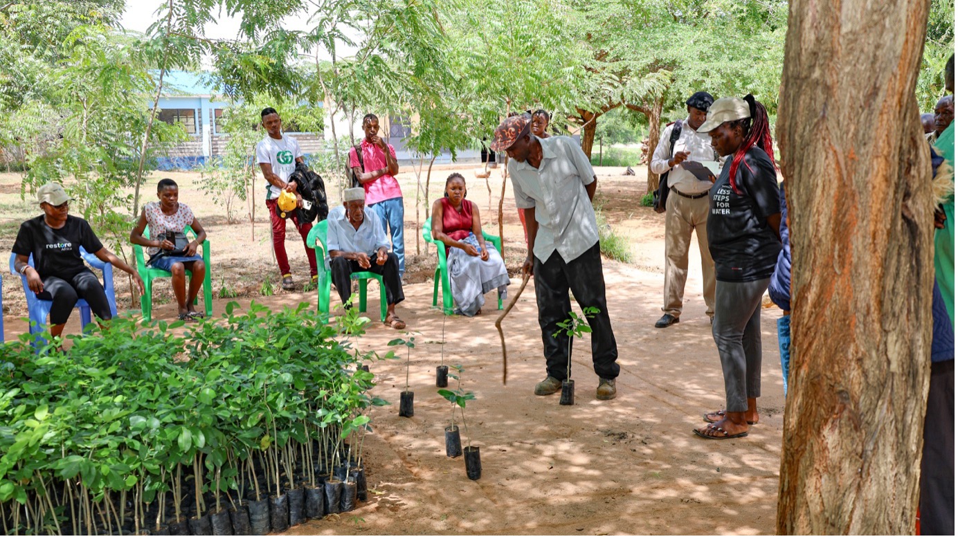 A farmer in Sokoke, Kilifi County, demonstrates proper tree planting and spacing methods to his peers during a Restore Africa tree distribution exercise.