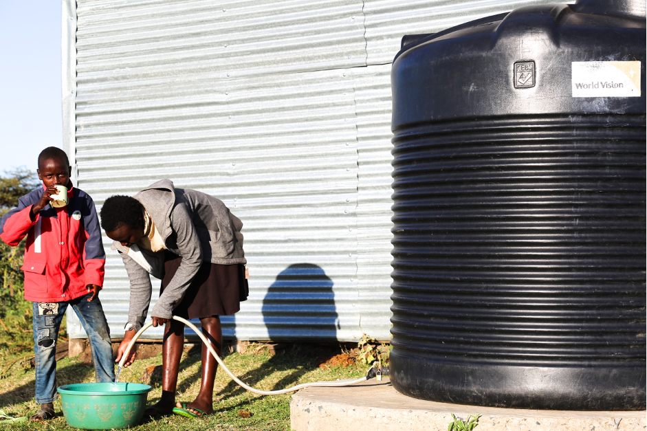 Zipporah fetching clean water for domestic use from a water storage tank donated to the family by World Vision. 
