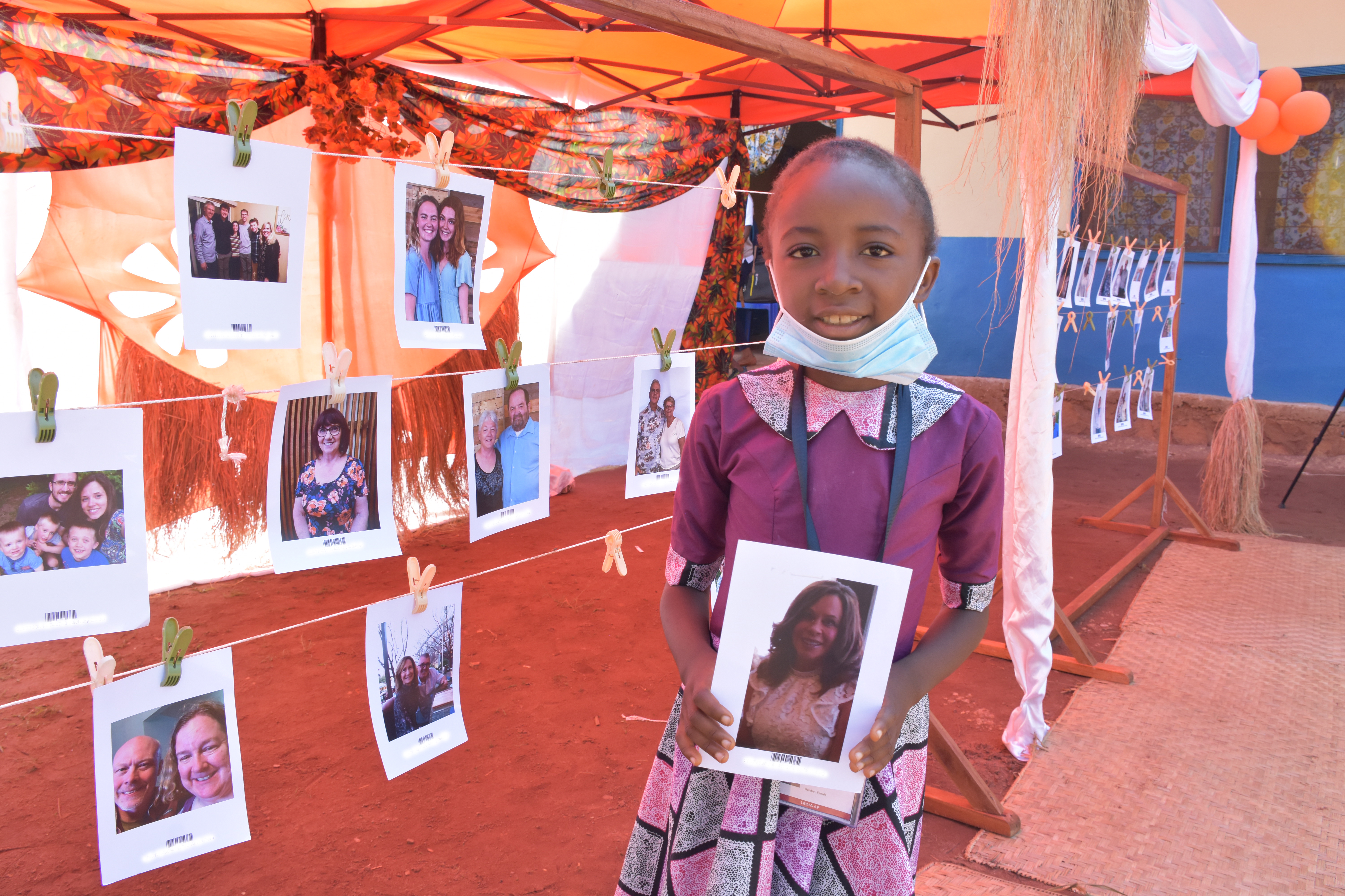 An excited Plamedie posing with a photo of her new sponsor
