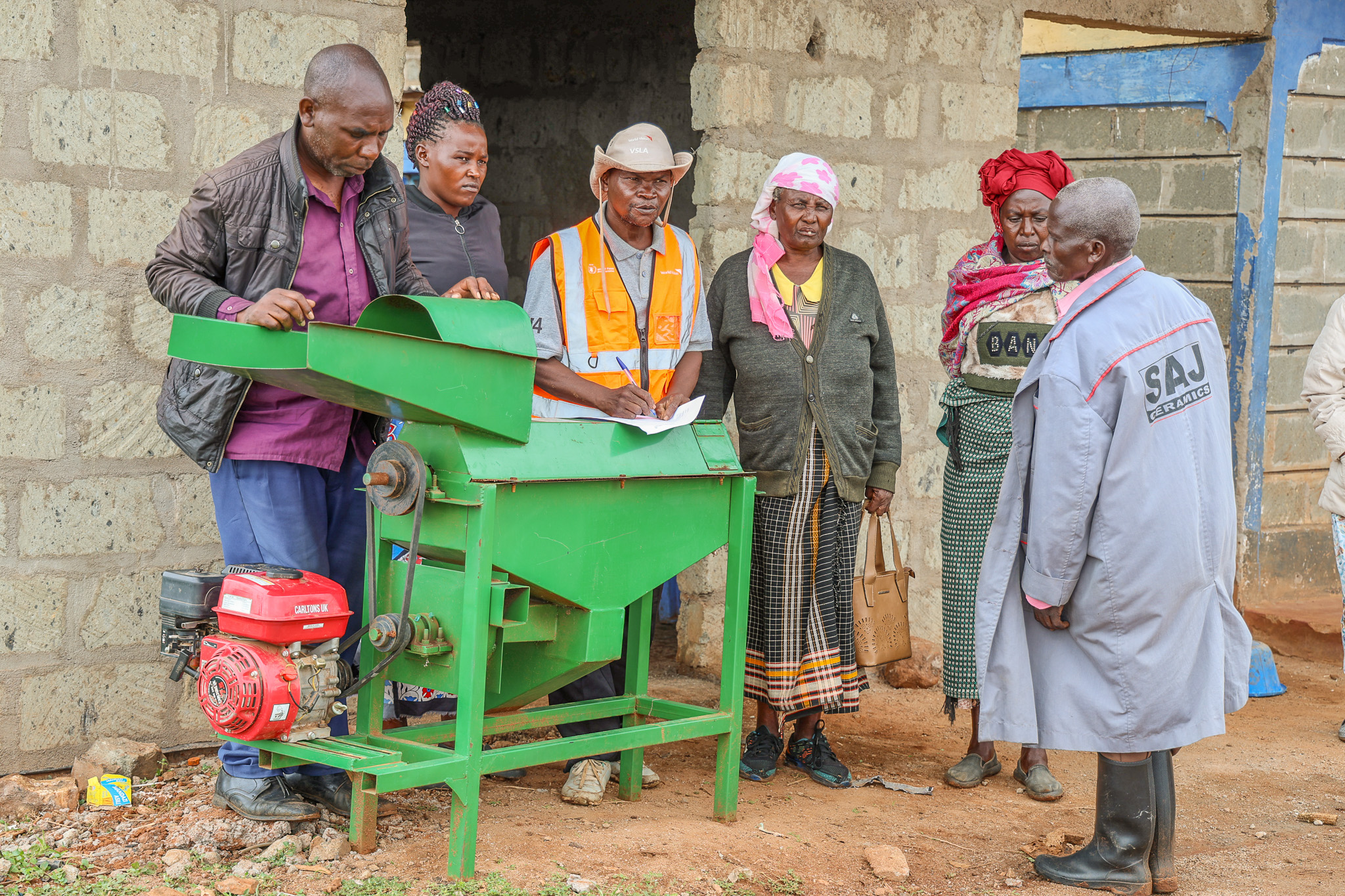 Alfred Muema, Village Agent and member of Mauseo Kivunga “A” VSLA, reviews group records ahead of a weekly table banking session in Kanyonyo Village, Kitui. Also pictured is the shredder machine the group purchased last year. © World Vision Kenya/ Jared Ontobo