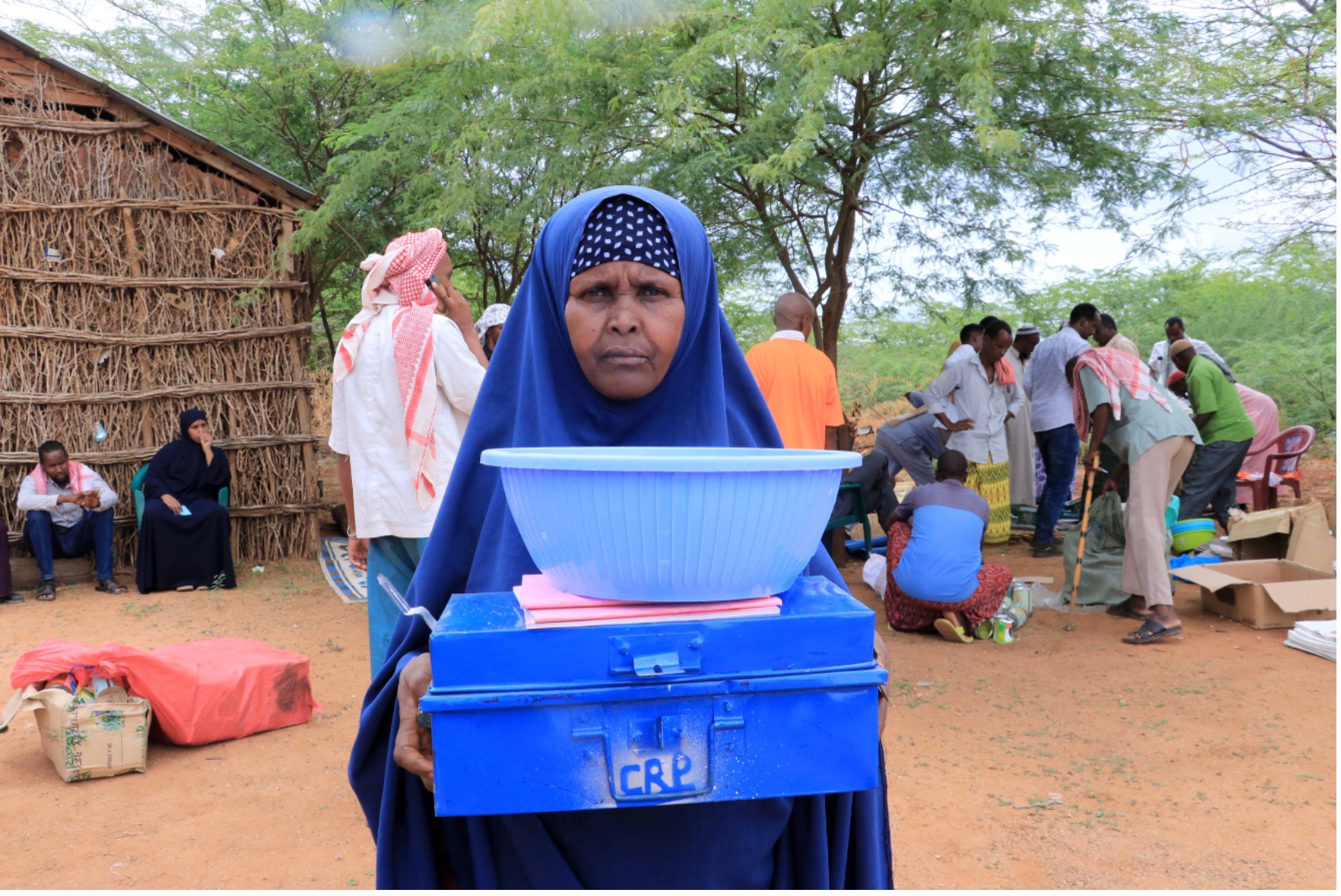 Gini, a VSLA member in Luuq District, displays her group’s savings kit including a lockbox, record book, and social fund bowl.