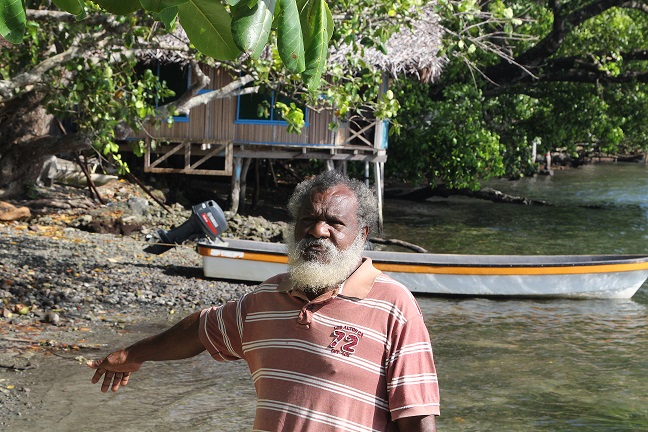 Kamas Sapom, a community leader in Riwo pointing to where there was once land before the impact of Climate Change.