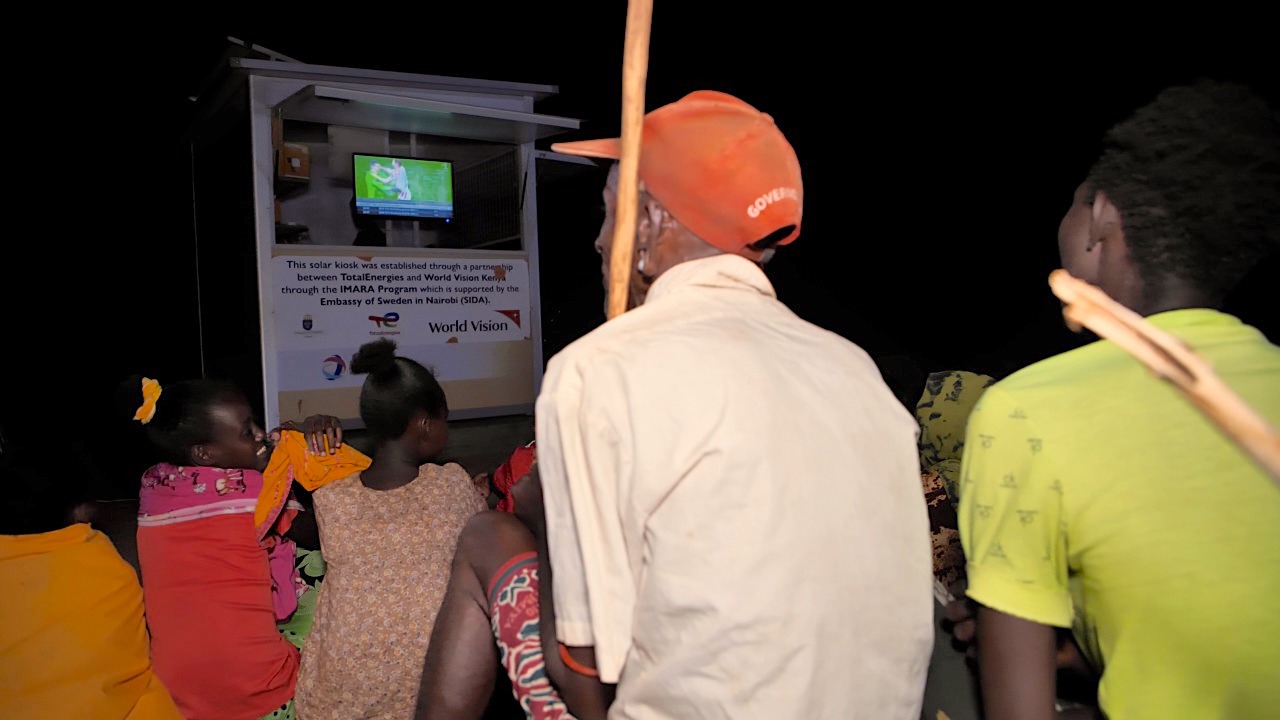 Residents of Ndikir village in Marsabit County gather around the solar kiosk to watch the 2022 FIFA World Cup.  The solar kiosk installed by World Vision in collaboration with TotalEnergies in Ndikir village. ©World Vision Photo/David Nderitu.