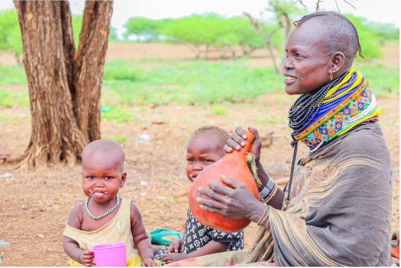 Akuam serves her children goat milk from the galla goats her family received through the support of World Vision through the K-DREAM Project. © World Vision Photo/Felix Pilipili