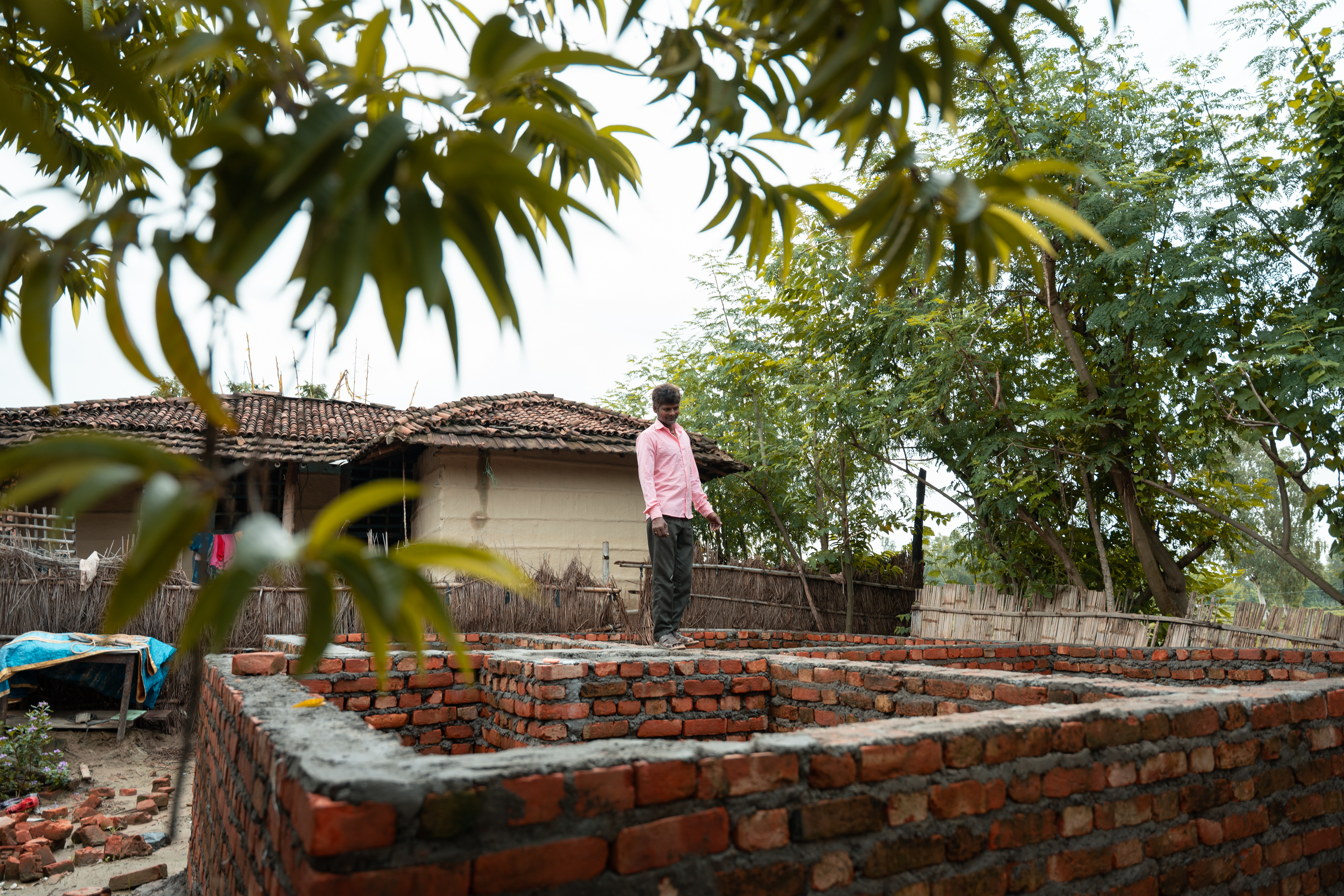  Satrudhan stands on the foundation of his family’s new home, envisioning the warmth and comfort it will soon provide. 
