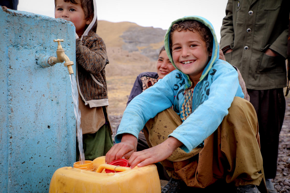 Young girl in Afghanistan collects clean water with a smile on her face