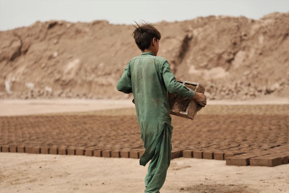 Child in Asia carrying bricks