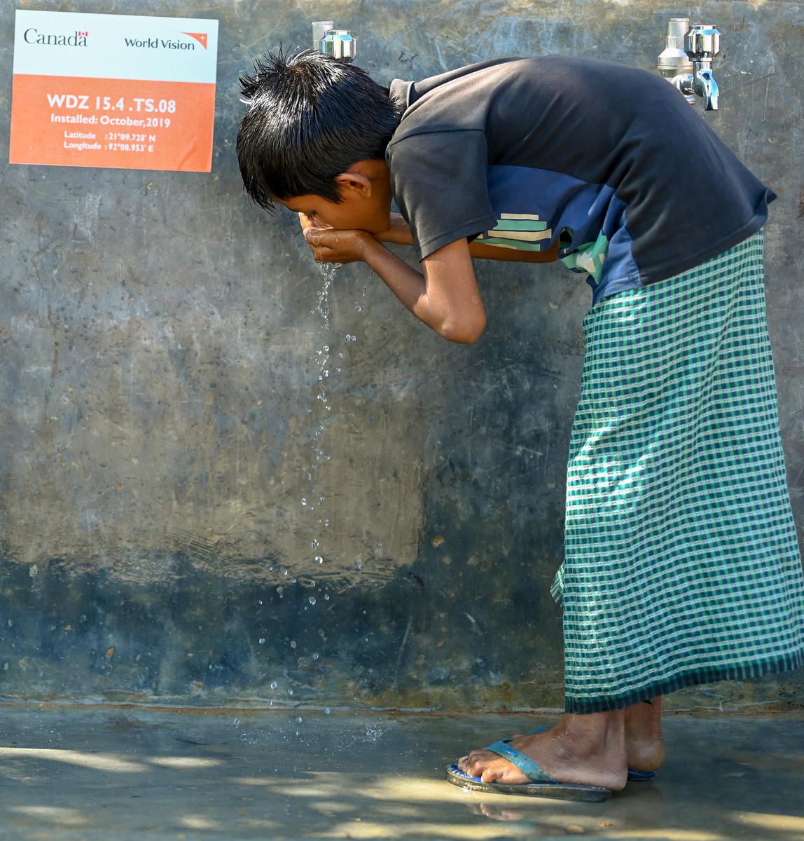 Shahanara’s son Mofij, 10, enjoys a drnk of fresh water from a tap stand near his home. The new water network provides 1,030 Rohingya and host community families with clean water. Photo: Himaloy Joseph Mree, World Vision