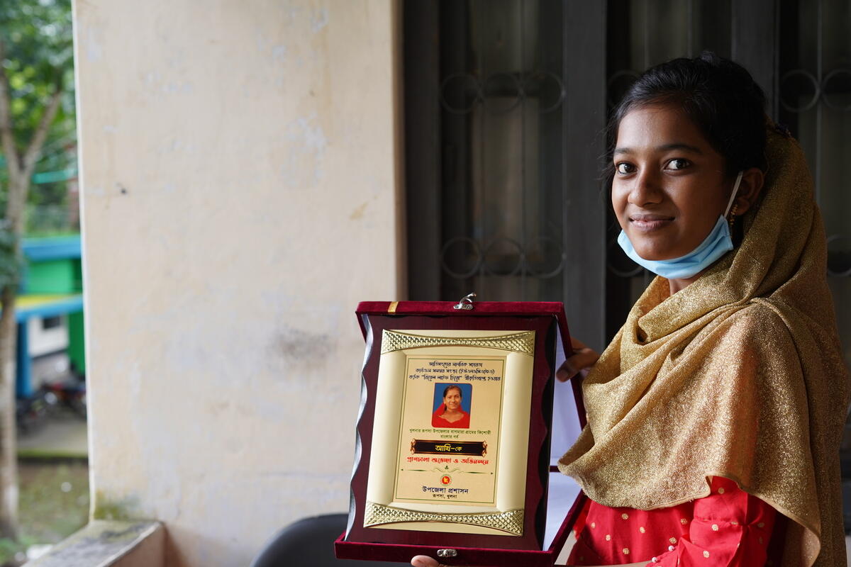 Akhi smiles as she holds her UNOCHA award.