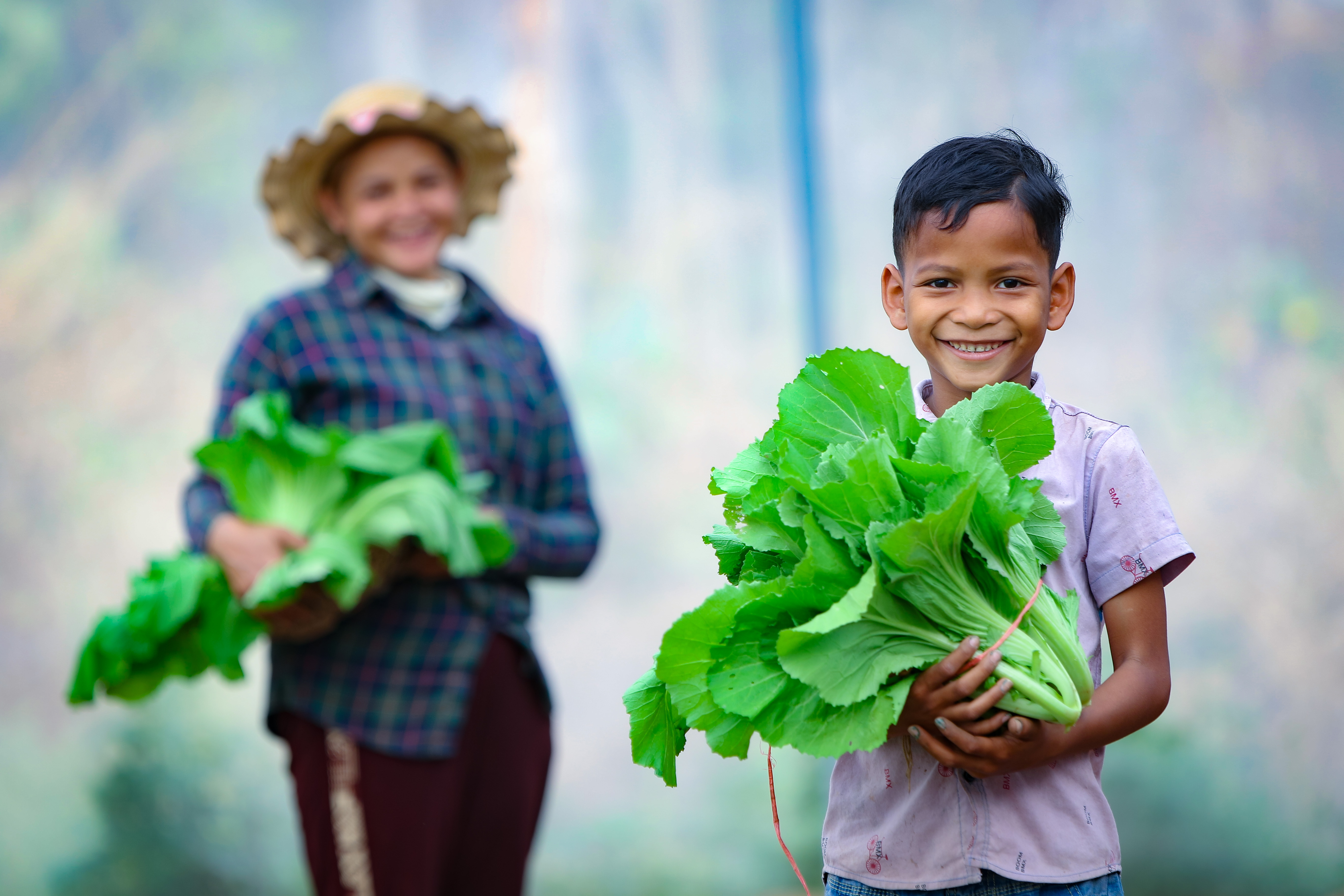 training on vegetable growing helps families fight nutrition in Cambodia, a mother and son walk with some of their harvested vegetables