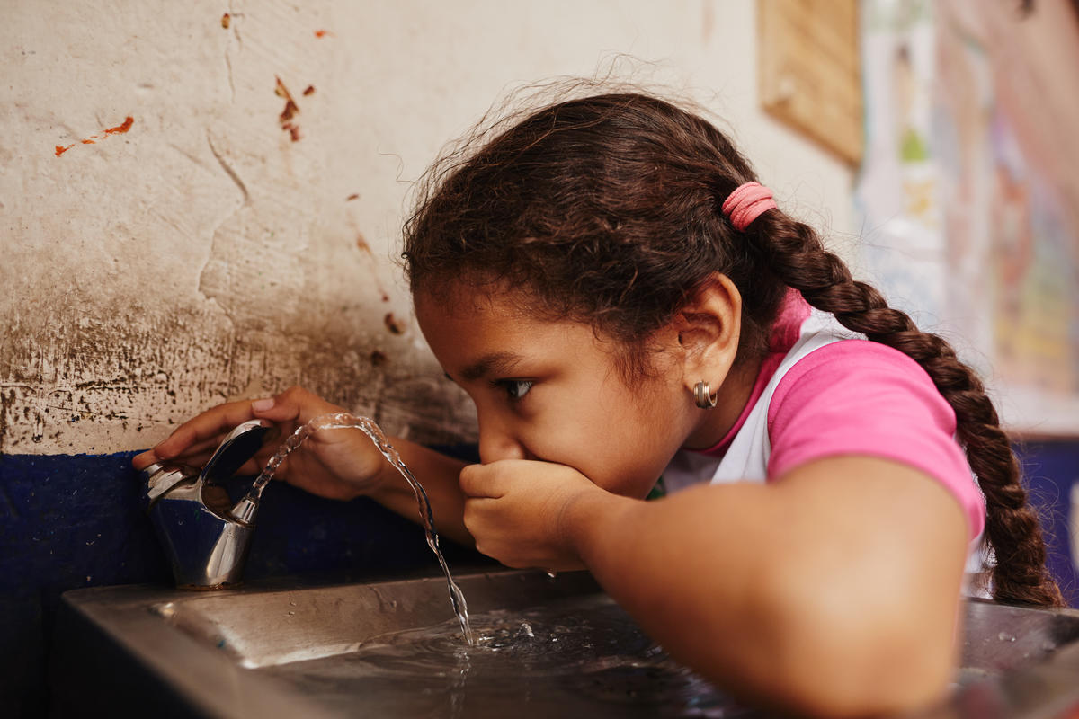 Sponsored child in Colombia drinks water from fountain World Vision helped install in her school