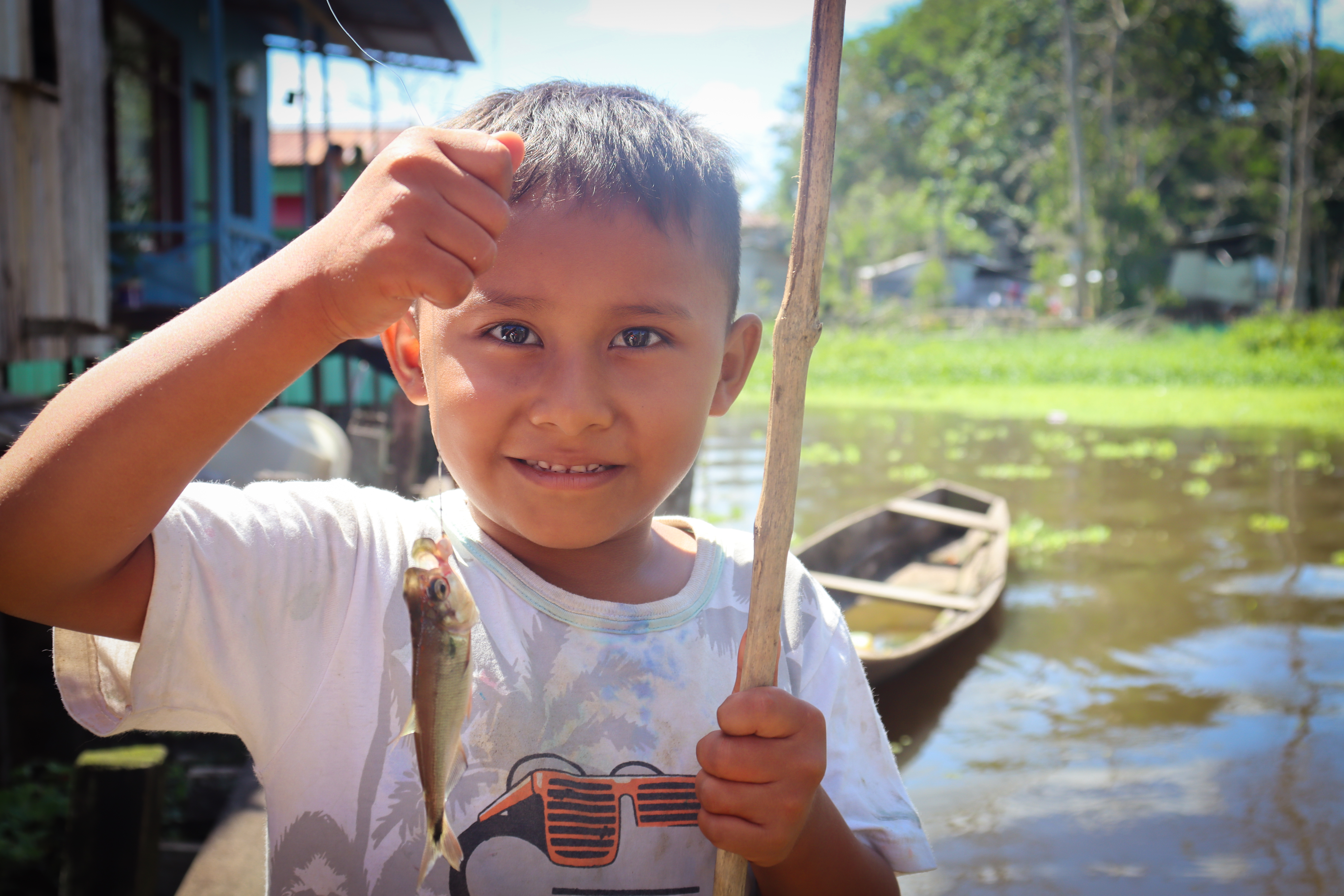 A child from Victoria Regia, an alluvial settlement in Leticia, proudly shows a small fish caught near the floodwaters